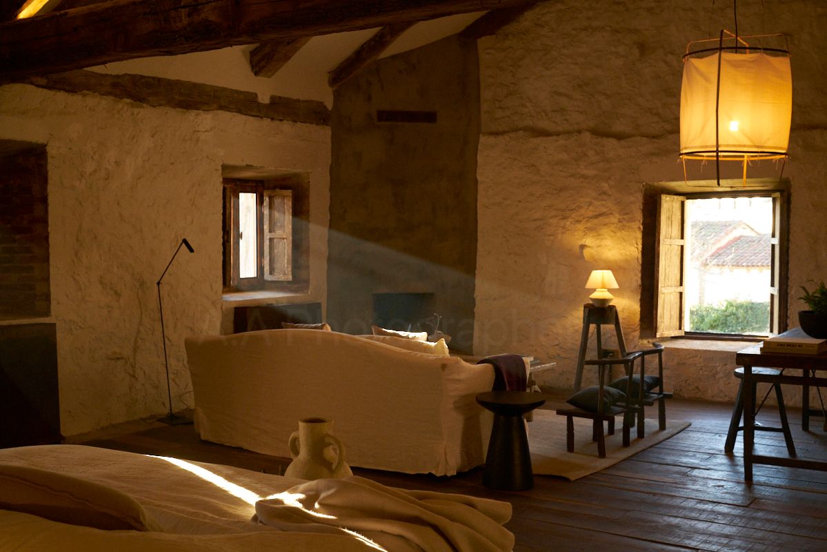 Cozy living room with stone walls, a couch, and sunlight streaming through windows.