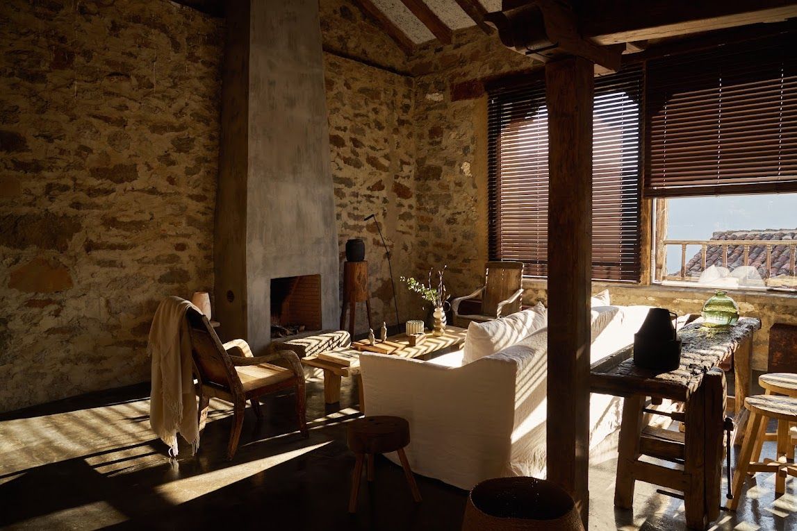 Rustic interior with stone walls, fireplace, and window overlooking a landscape.
