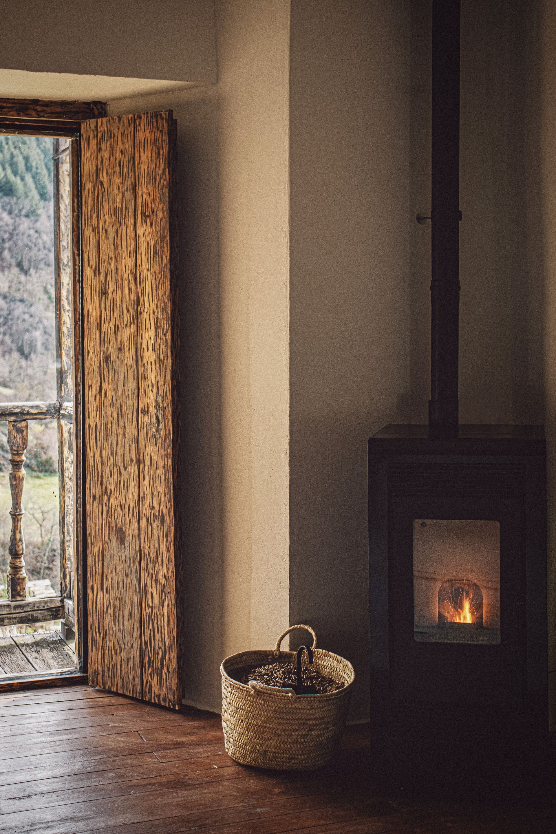 Cozy room with a fireplace and open wooden door leading to a balcony. A basket sits near the fireplace.