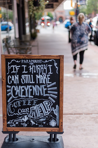Chalkboard sign on a sidewalk reads “If I had my way, I’d still be the flower in your hair.”