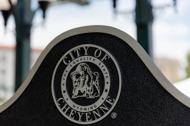 City of Cheyenne seal on a black sign, with blurred buildings in the background