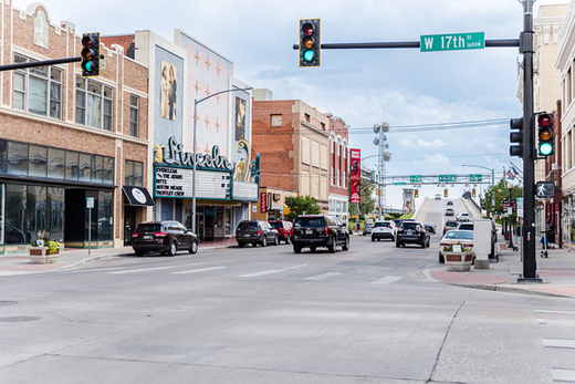 Downtown street with cars, traffic lights, and storefronts on a cloudy day