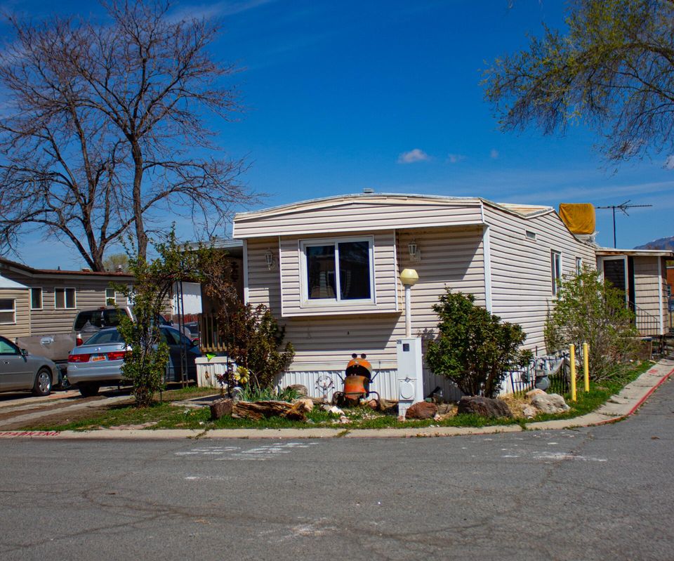Front of a mobile home with trucks in the driveway at South Springville Mobile Home Park