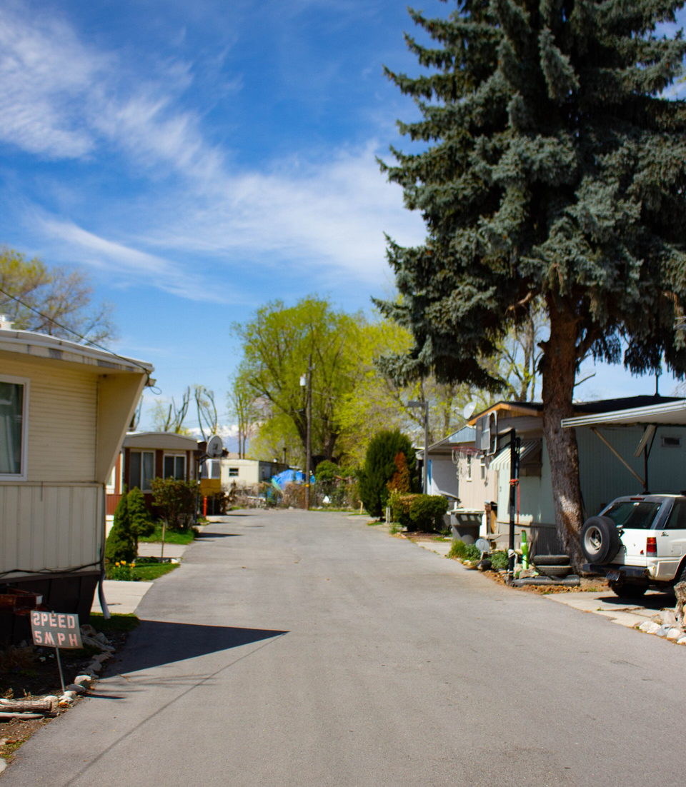 Front of a mobile home with trucks in the driveway at South Springville Mobile Home Park
