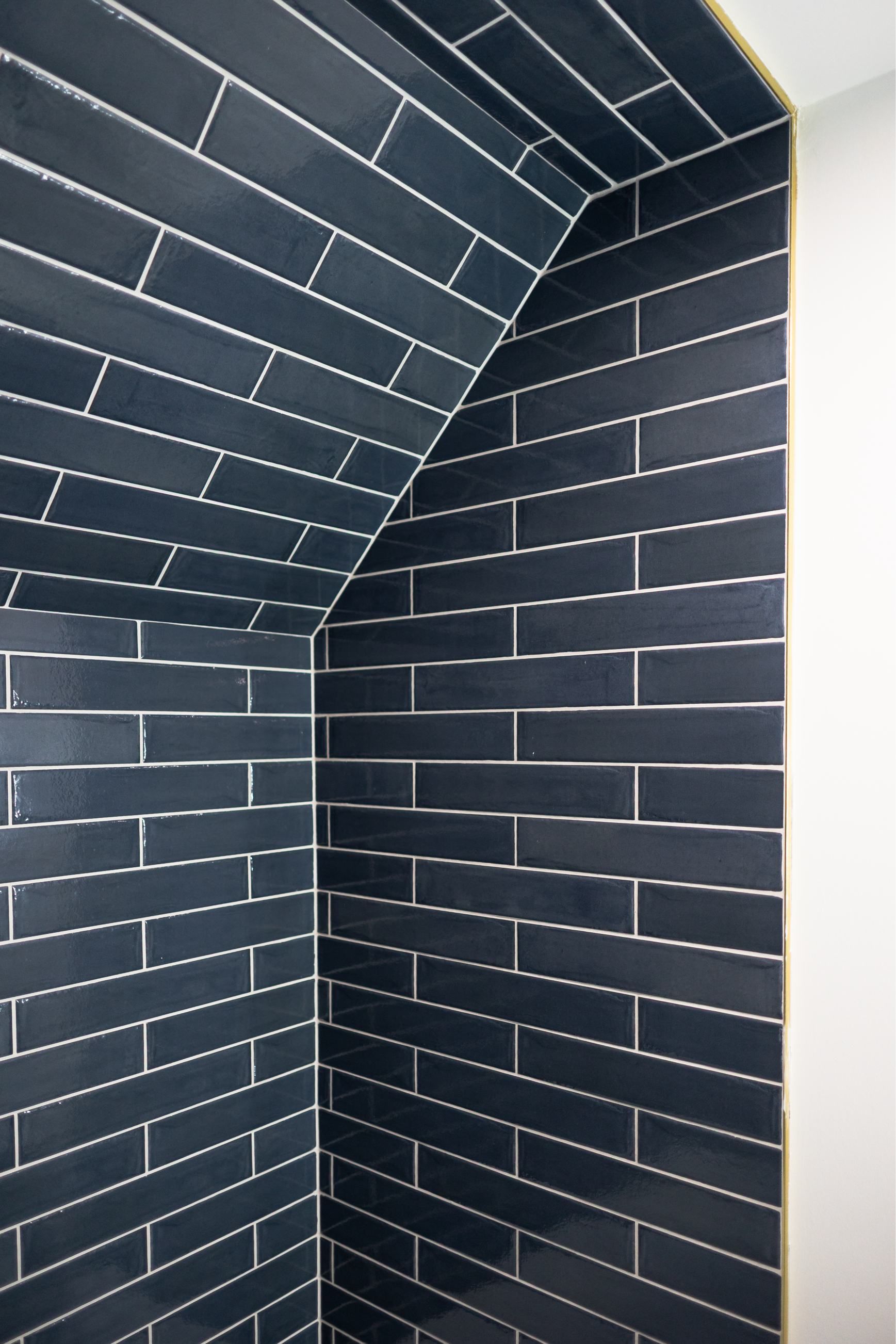 Dark blue tiled alcove with white grout and a slanted ceiling corner