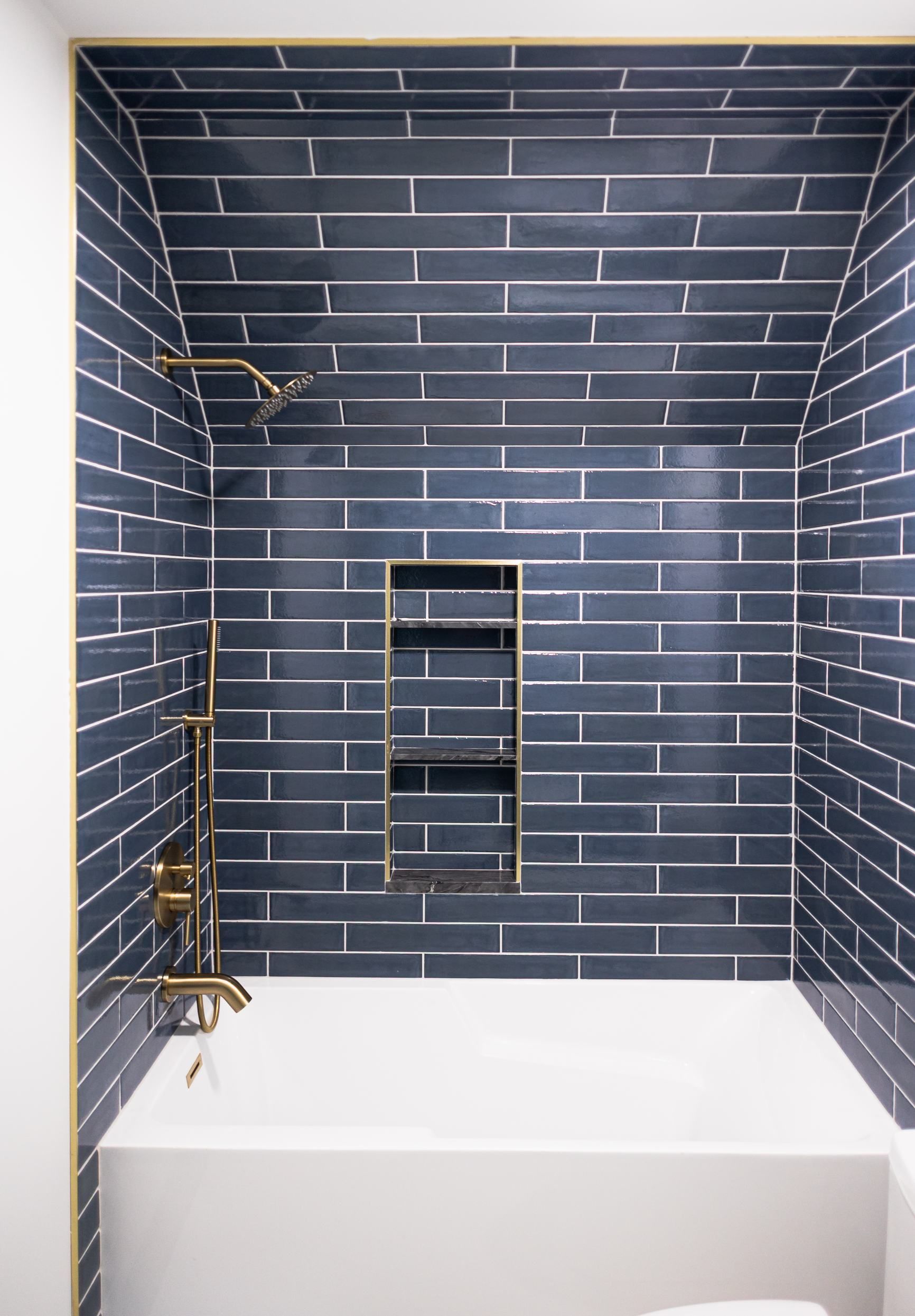 Blue-tiled shower with a white bench and a recessed niche in the back wall