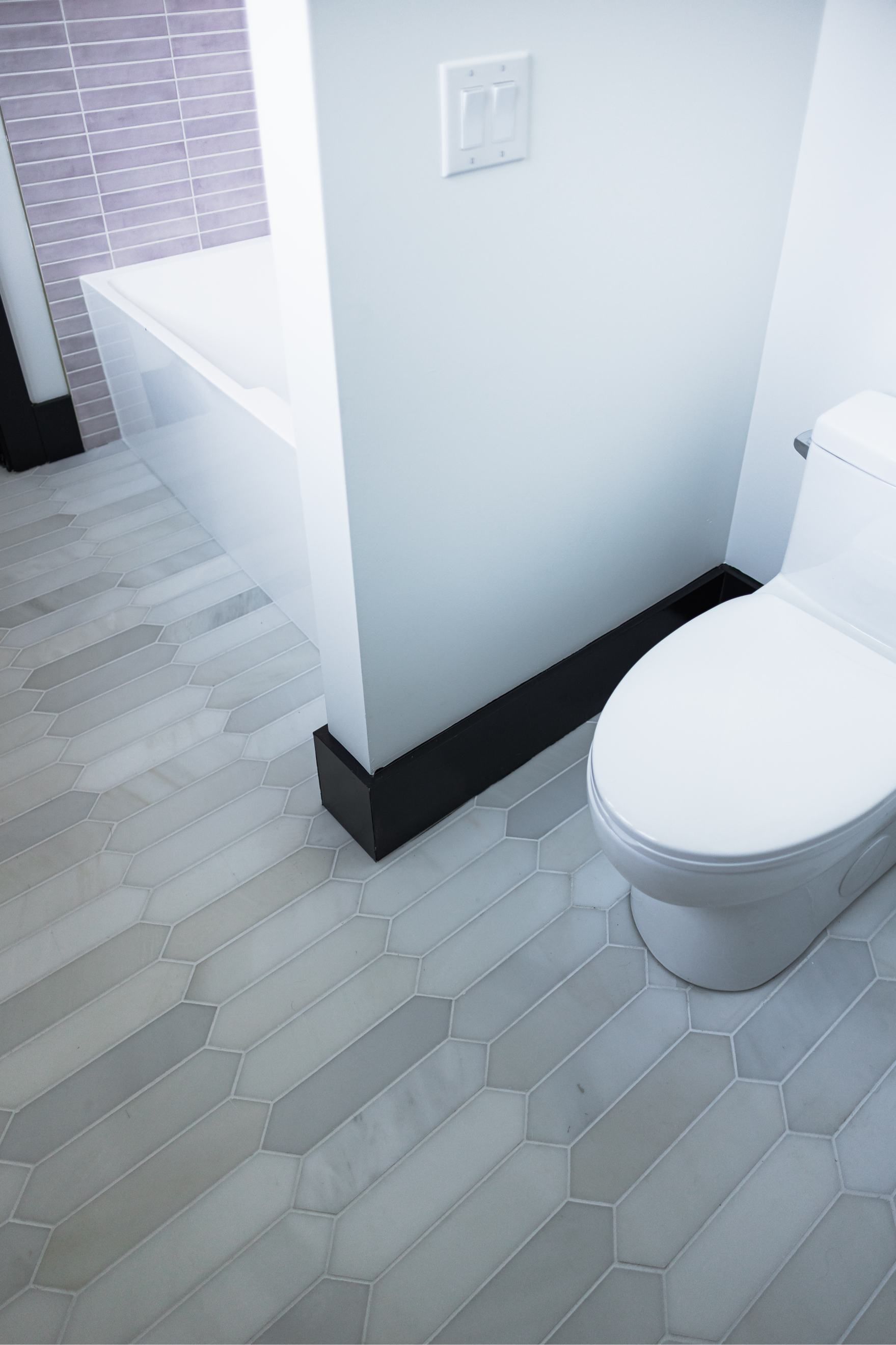 Small bathroom with a white toilet, gray floor, and partition wall near a shower area