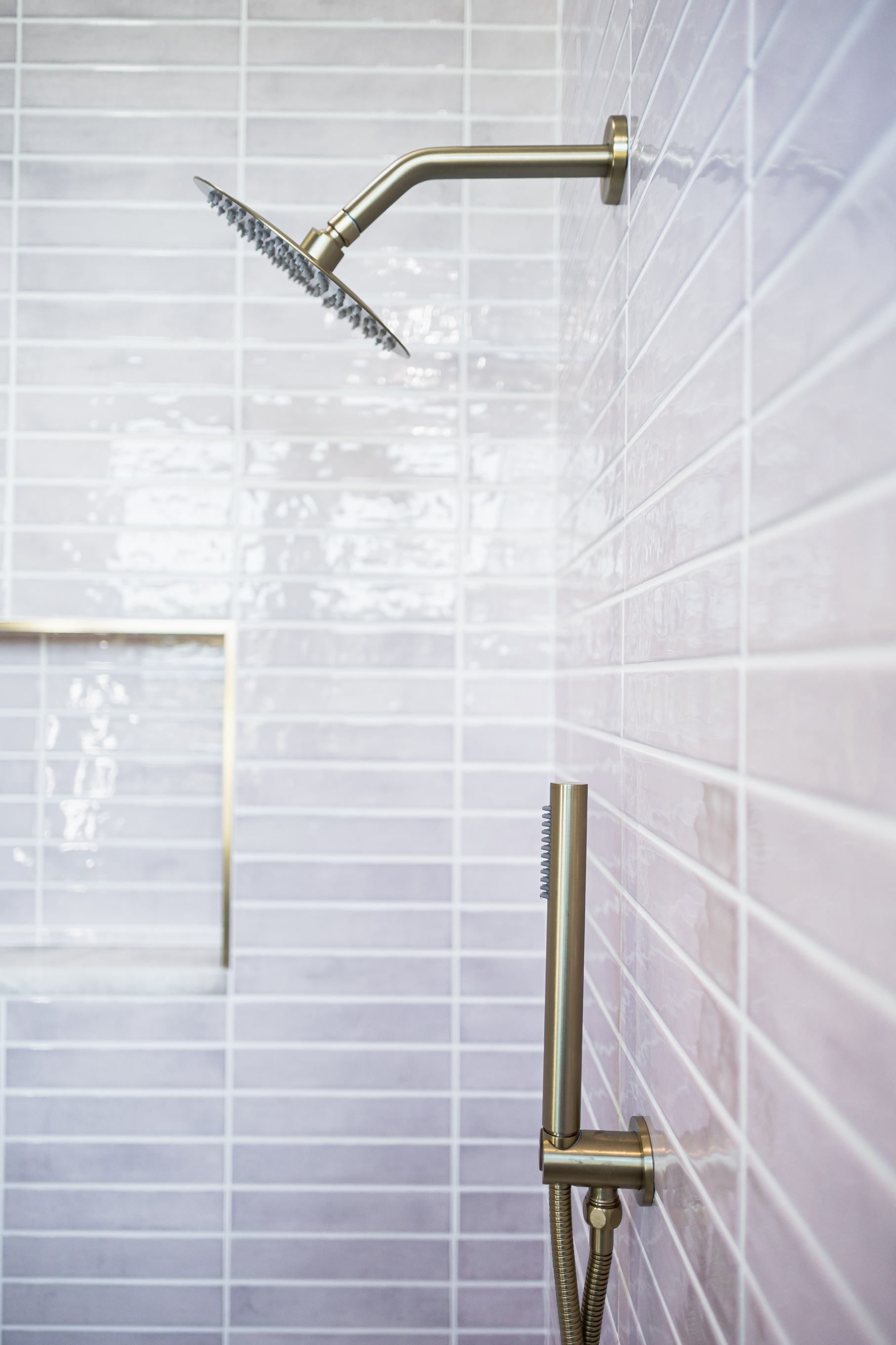 Modern tiled shower with two brass shower heads and a glass panel divider