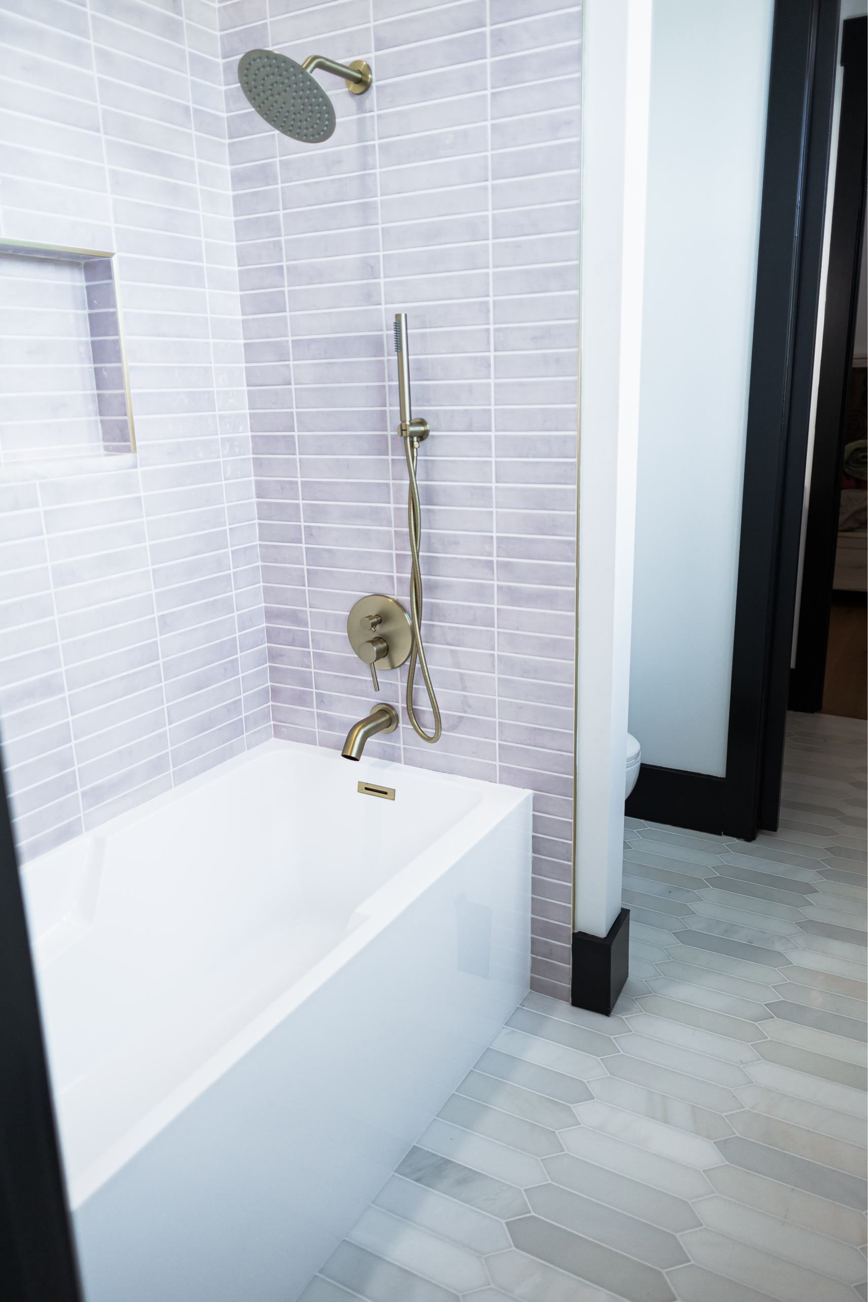 Modern bathroom with white tiled walls, a bathtub, and a chrome shower fixture