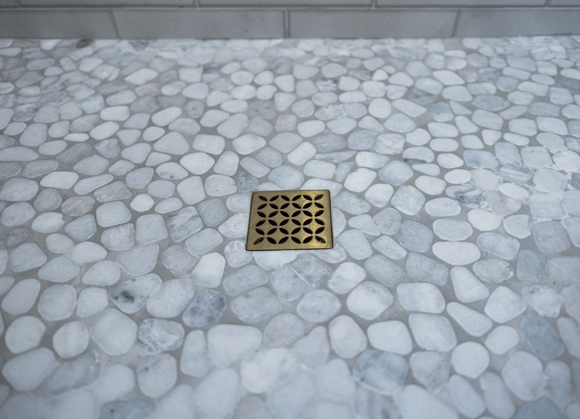 Stone floor with a central metal drain grate against a gray wall.