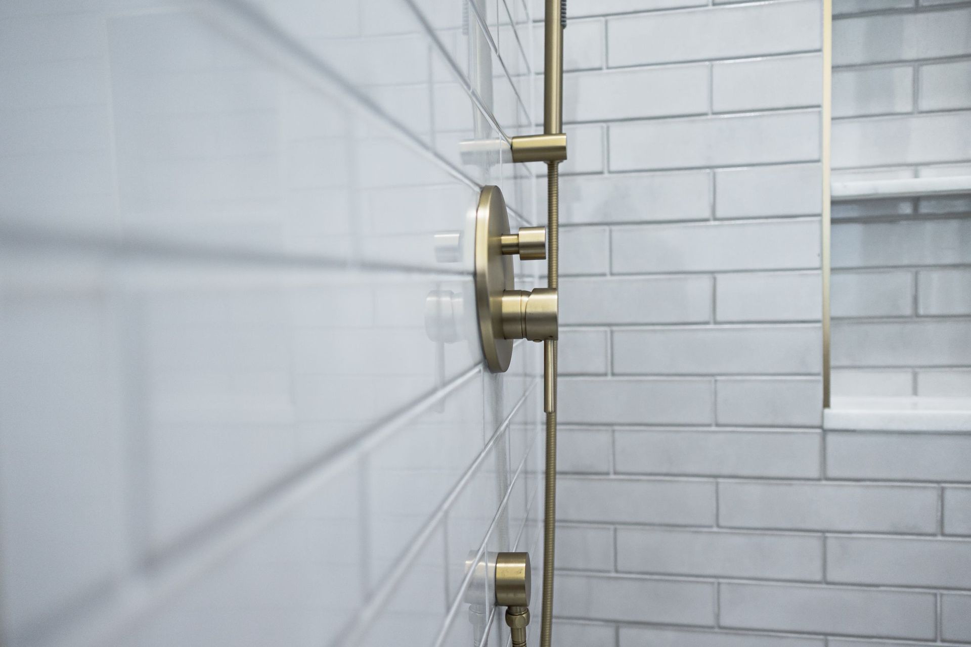 Modern shower with brass fixtures and white subway tile walls