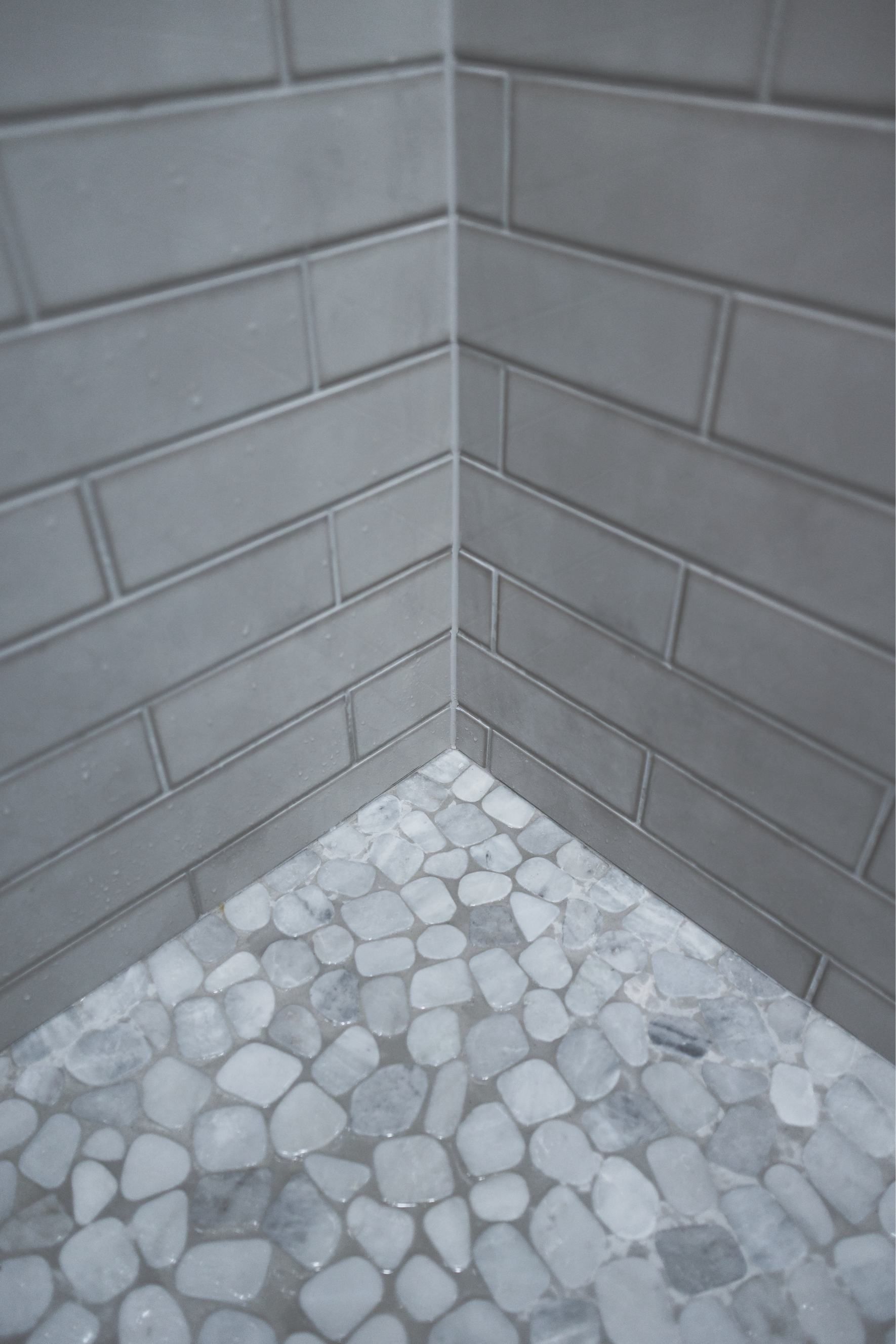 Corner of a gray brick wall with a white pebble-stone floor