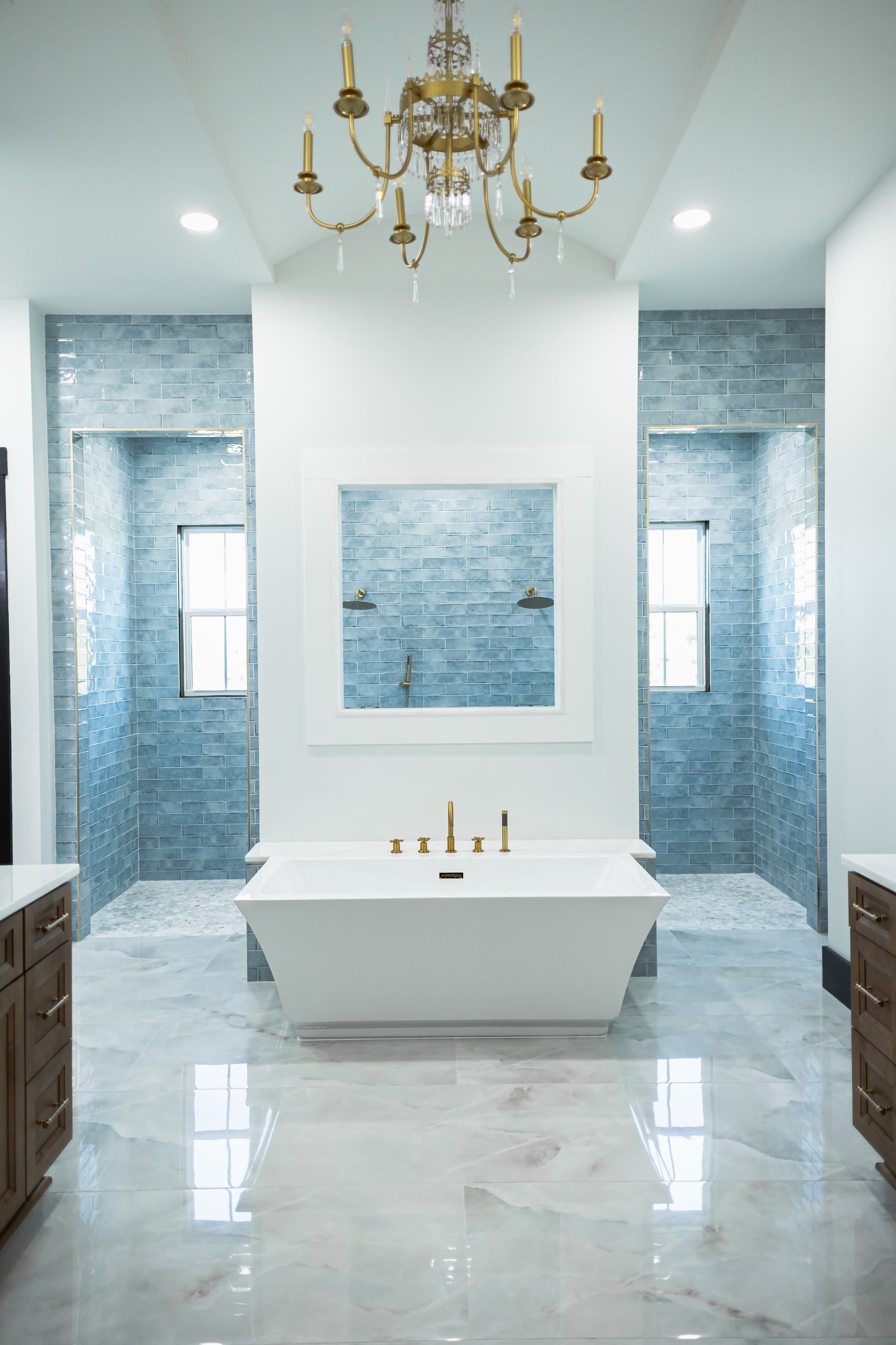 Elegant white marble bathroom with blue tile accents, chandelier, and freestanding tub