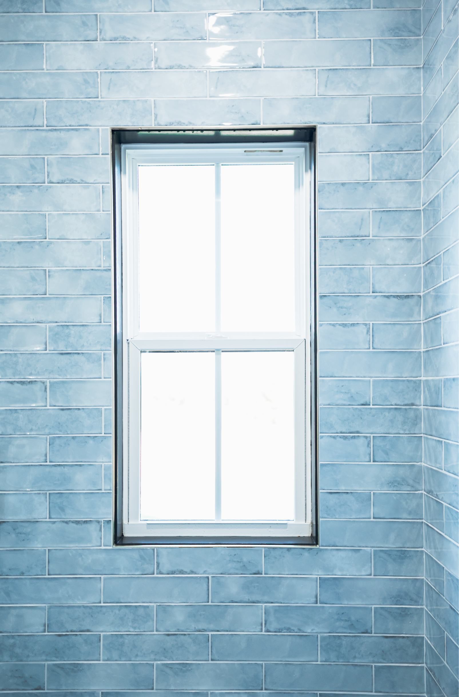 A white-framed window set in a light blue brick wall