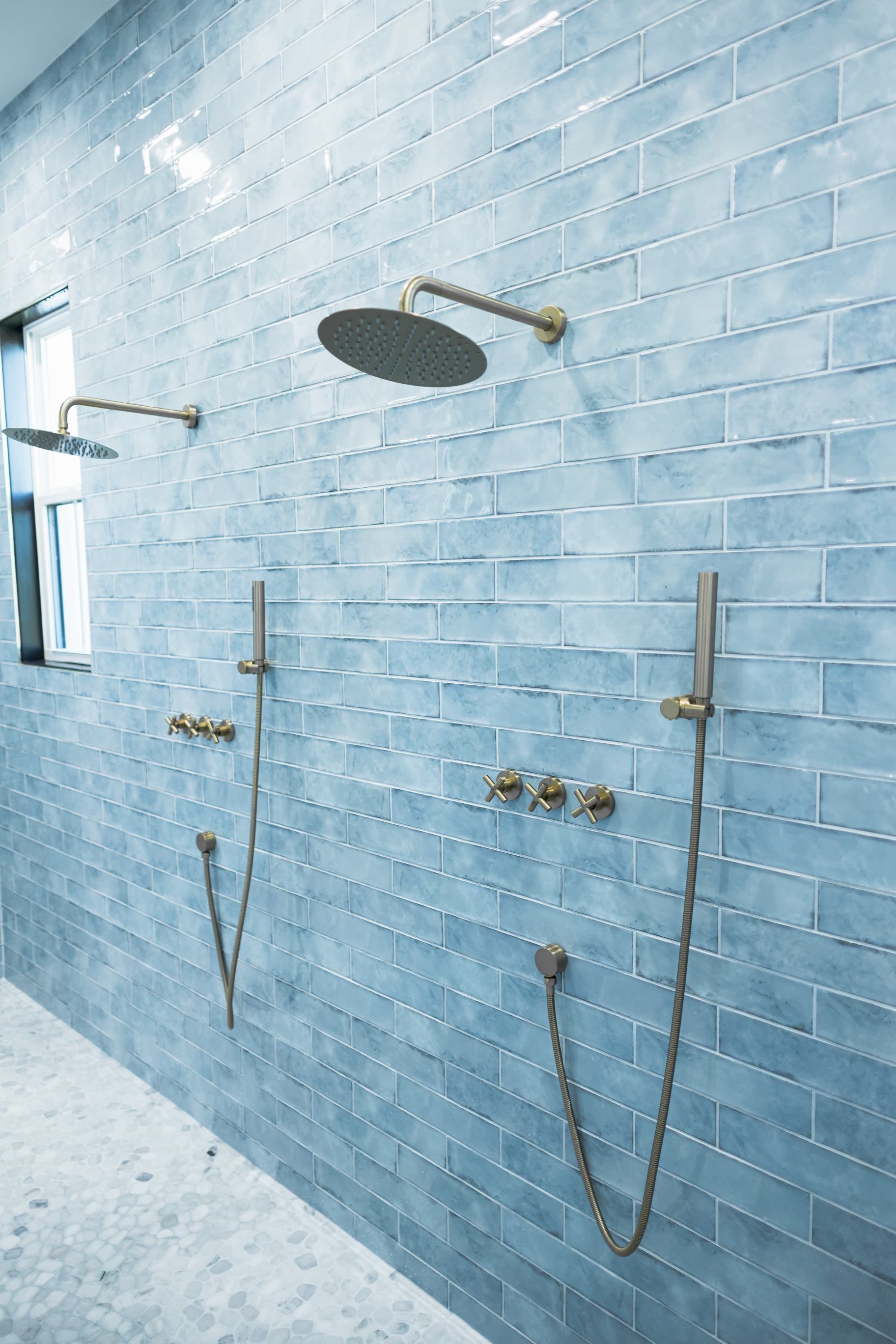 Blue-tiled bathroom with multiple showerheads and brass fixtures in a spa-like shower area