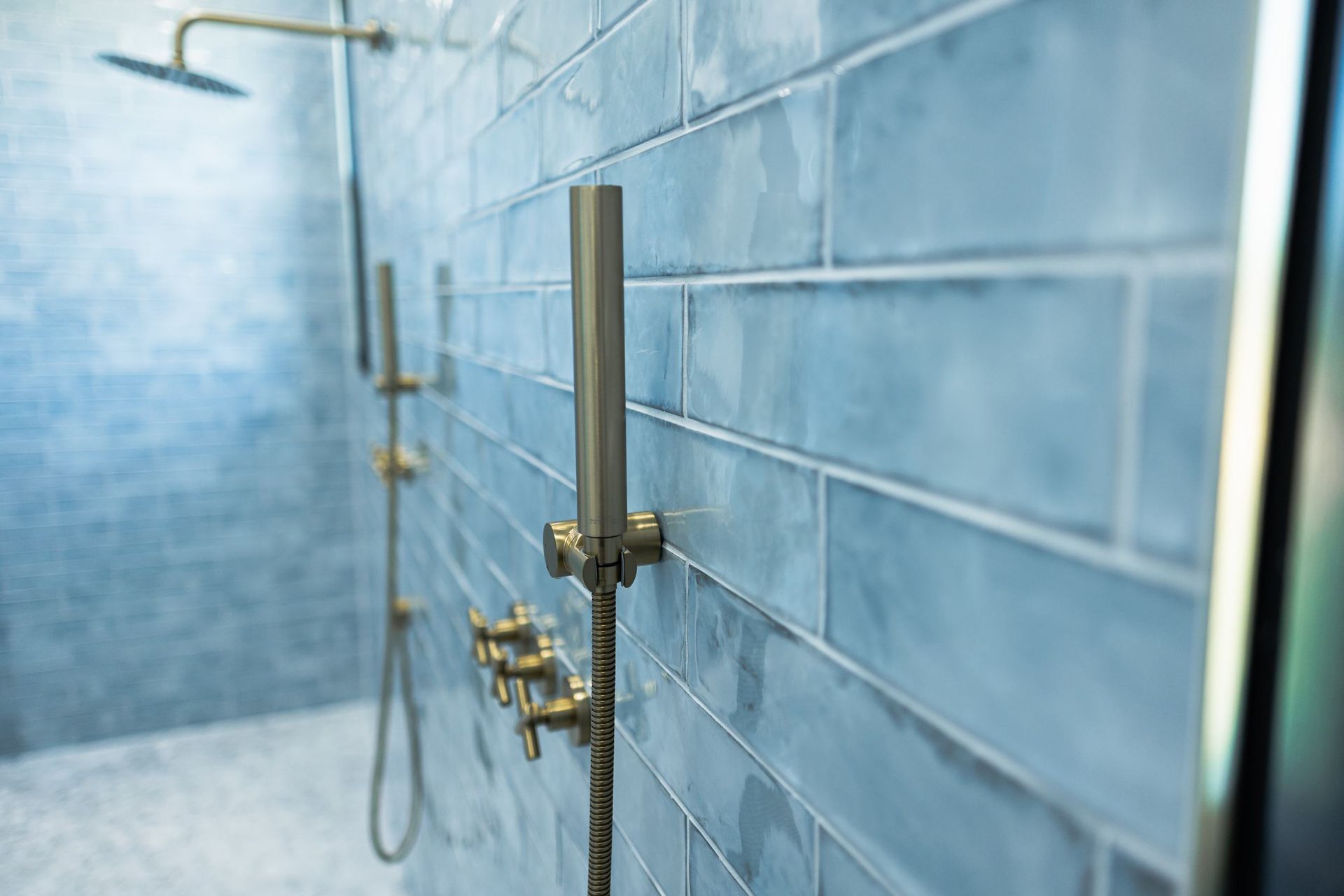 Modern shower with blue tiled wall and chrome fixtures in a bathroom