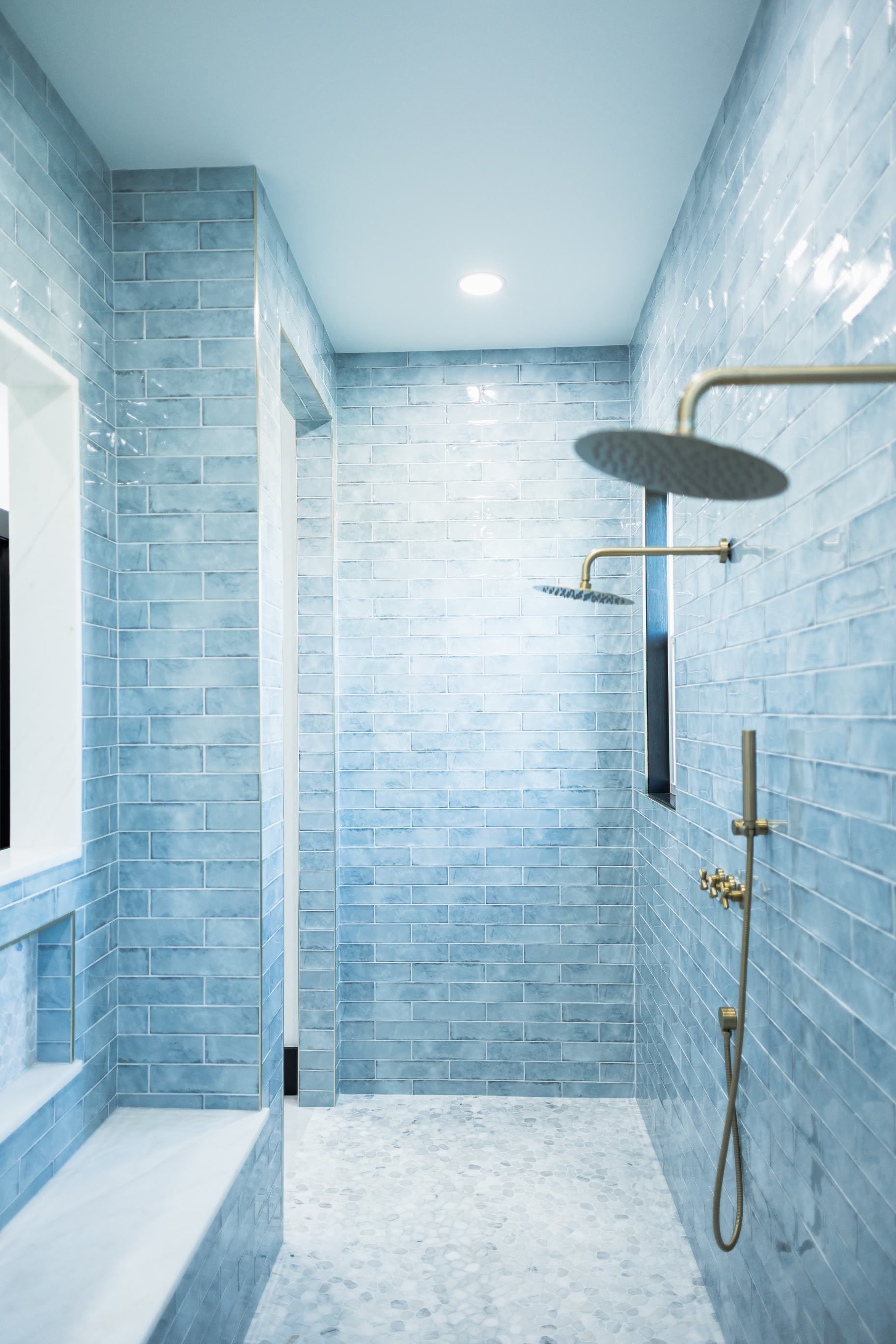 Blue tiled walk-in shower with rainfall showerhead and bench seat