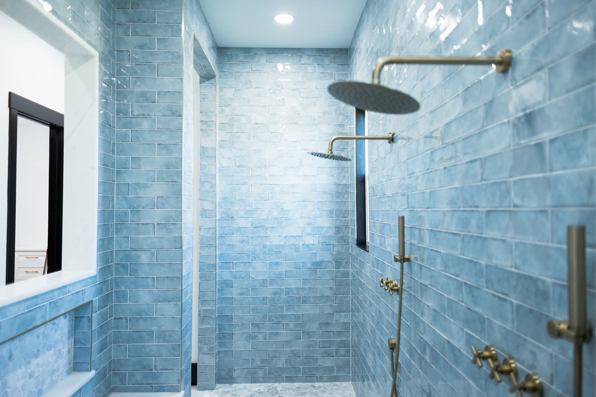 Blue-tiled bathroom with glass shower enclosure and rainfall showerhead