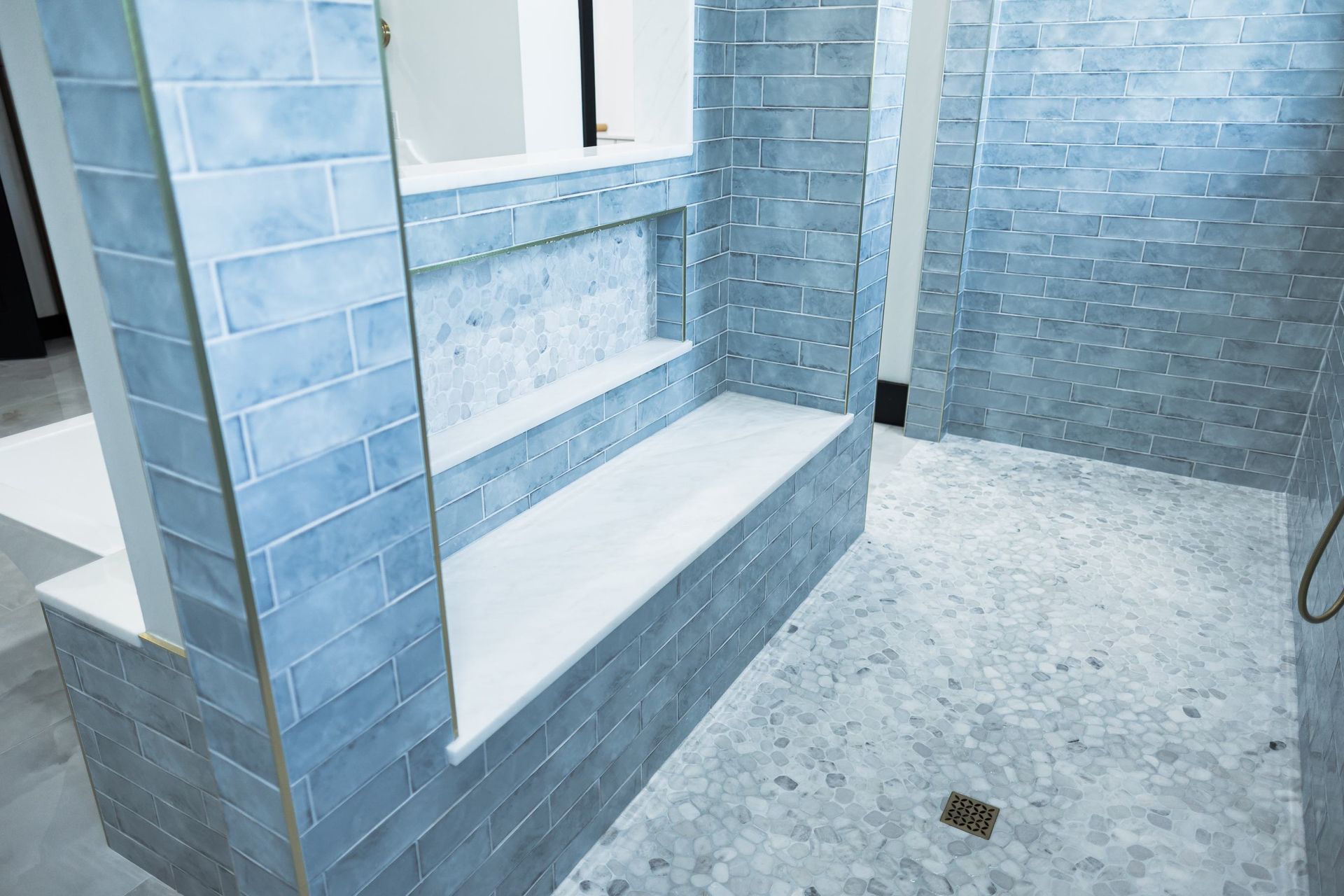 Blue-tiled shower with built-in steps and gray floor tiles