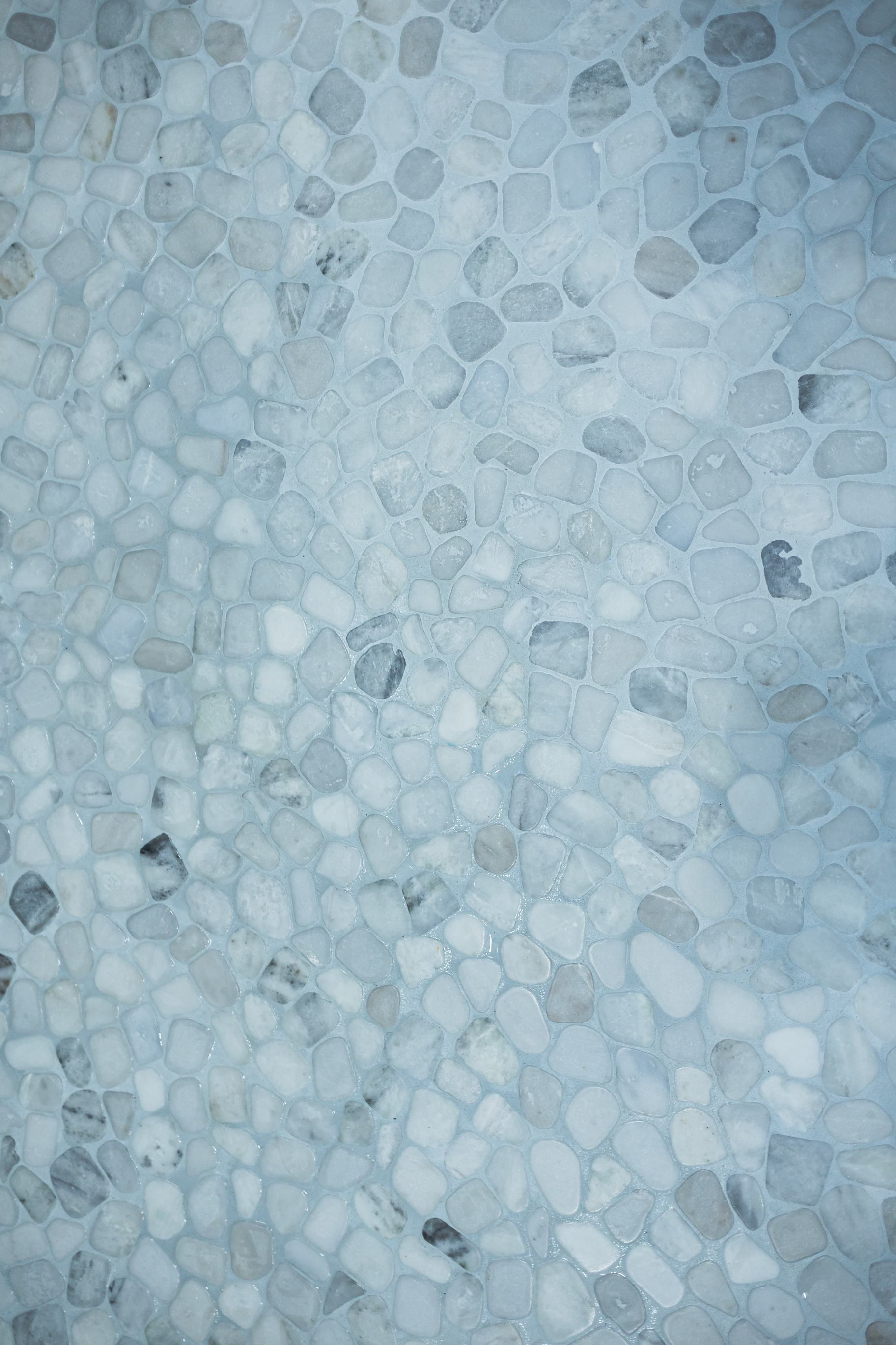Close-up of light blue-gray pebbled stone or mosaic surface with scattered darker stones