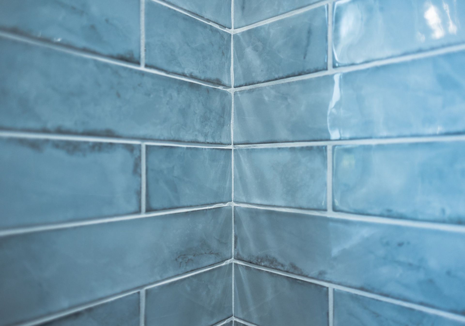 Blue tiled corner wall with white grout lines in a bathroom or shower area