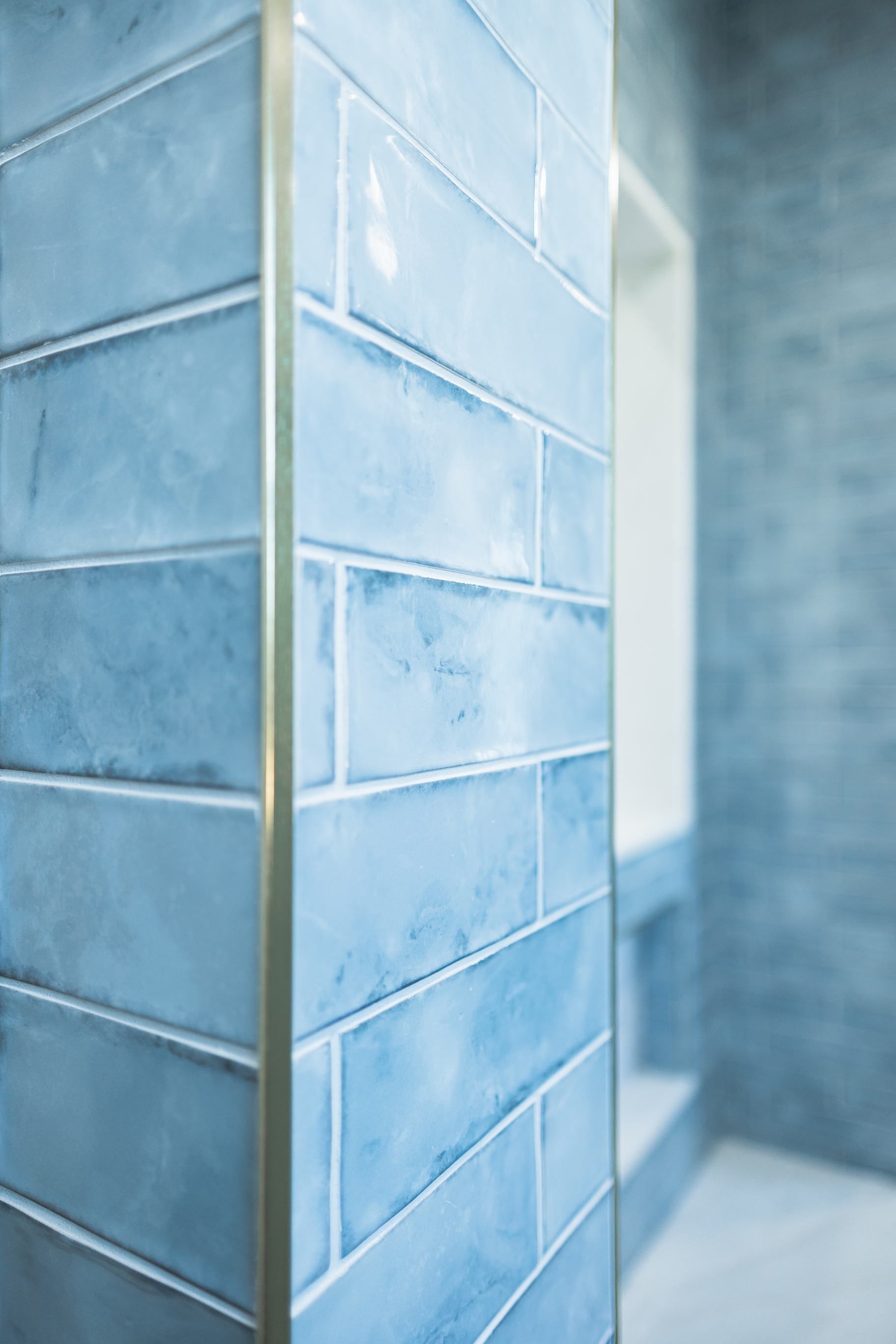 Blue tiled corner wall with white grout in a bright hallway
