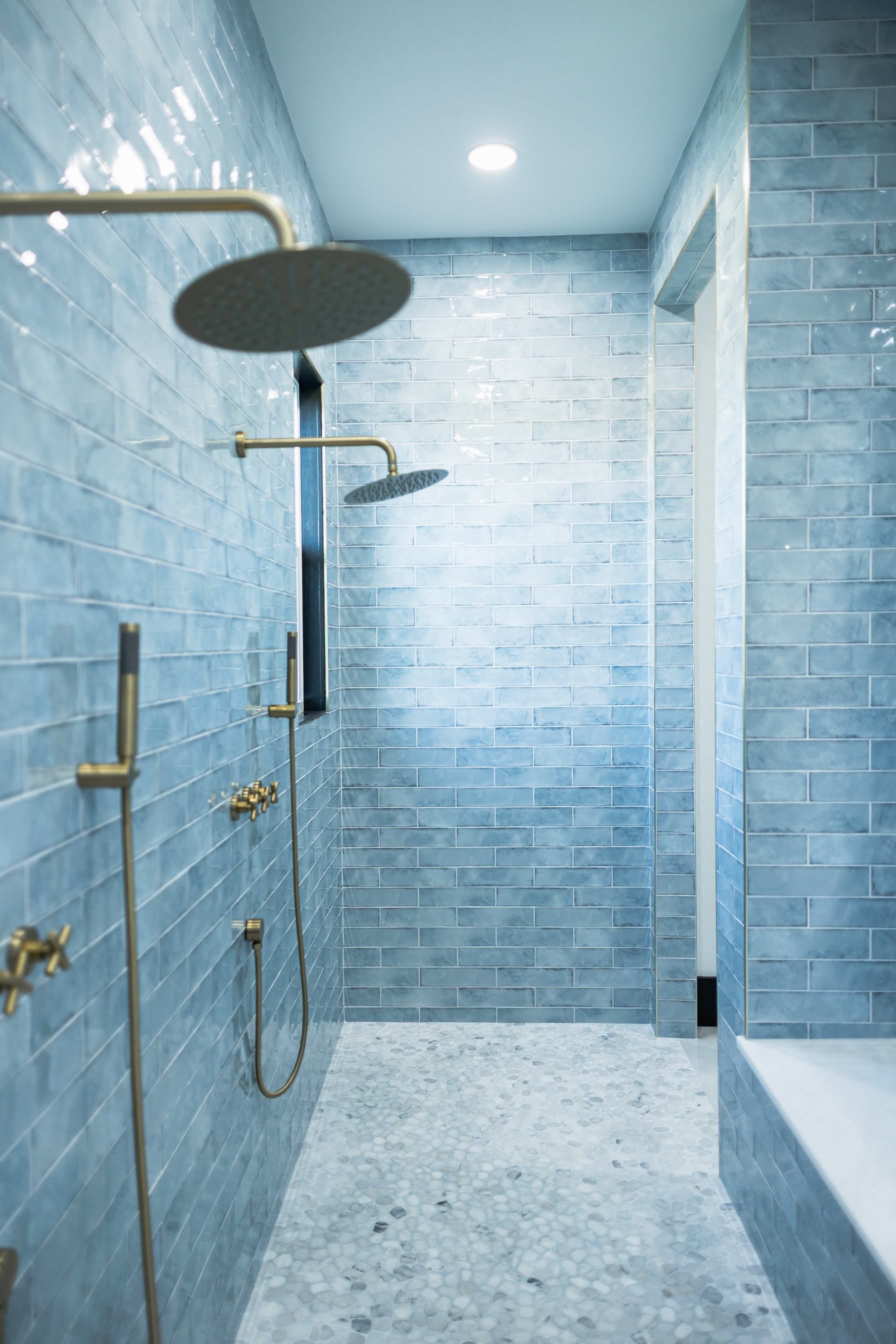 Modern bathroom with blue tile walls, walk-in shower, and rainfall showerhead