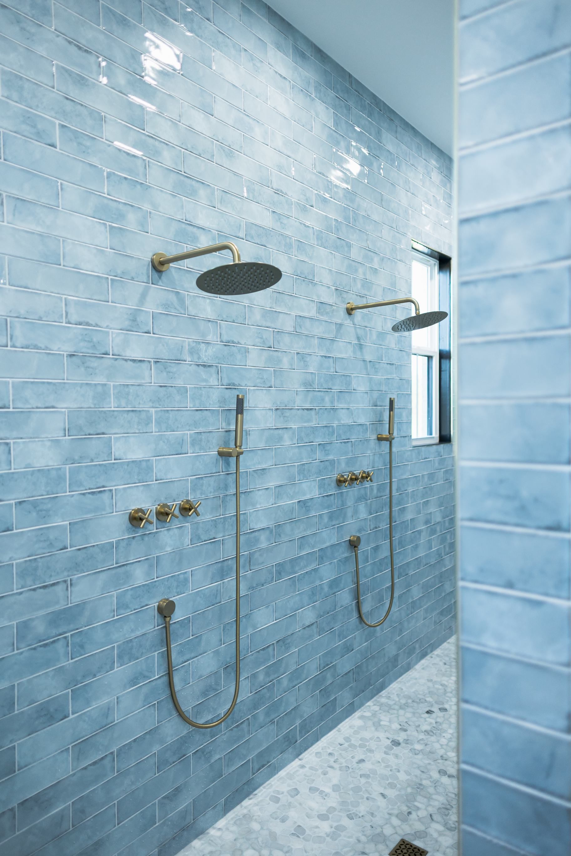 Blue tiled bathroom with dual showers and brass fixtures