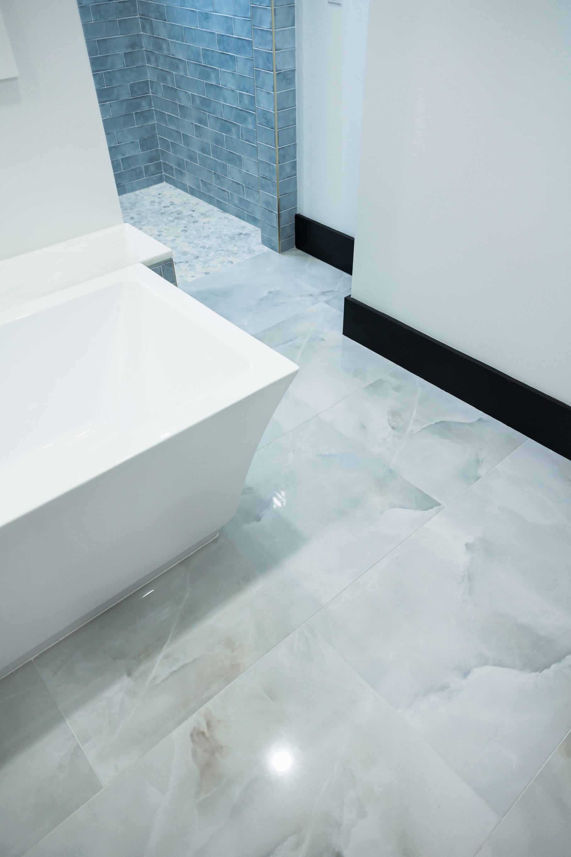 Modern bathroom with white vanity, gray marble floor, and tiled shower area
