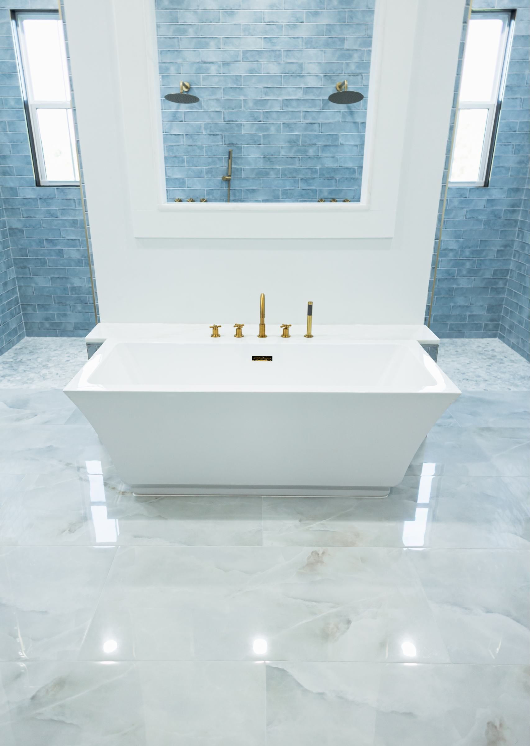 Modern white bathroom with a freestanding tub, marble floor, and blue-tiled wall niche