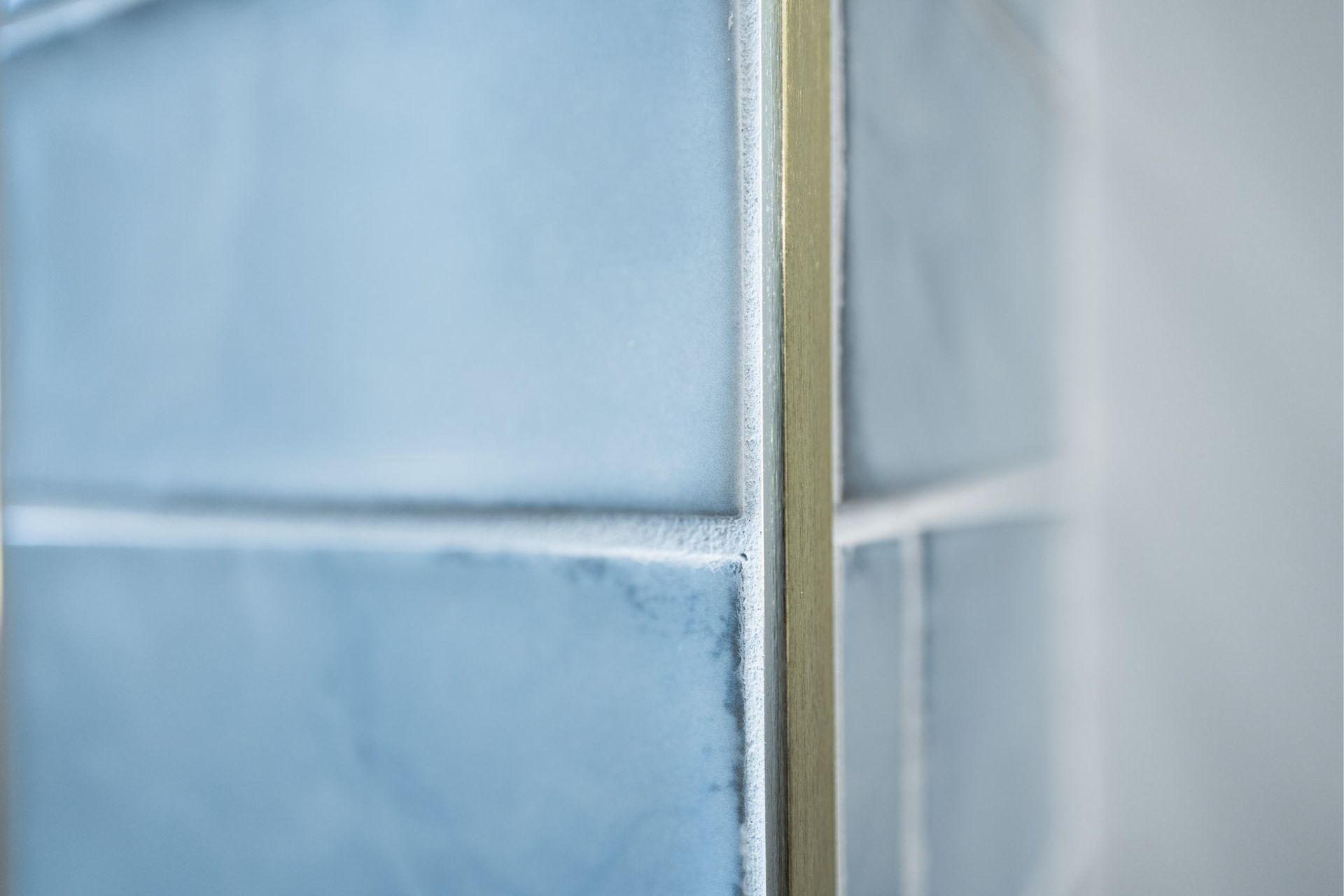Close-up of frosted blue glass panels with a metal frame in the center