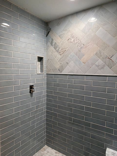 Marble shower with decorative tile niche and glass door.