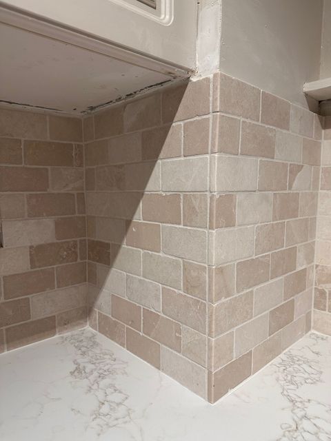 Light-colored ceramic tiles being installed on a floor, using tile spacers to maintain even spacing.