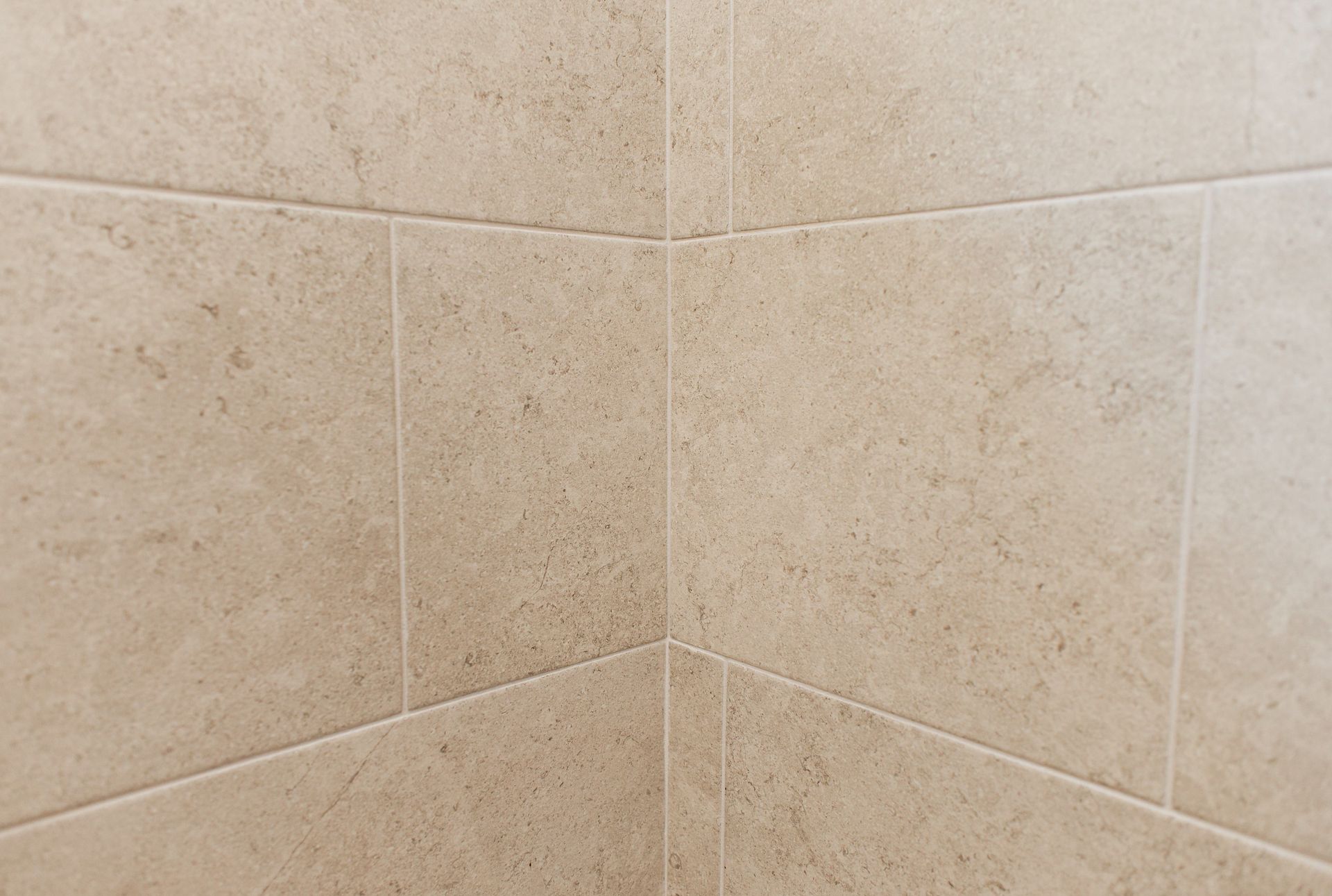 Beige tiled bathroom corner wall with grout lines
