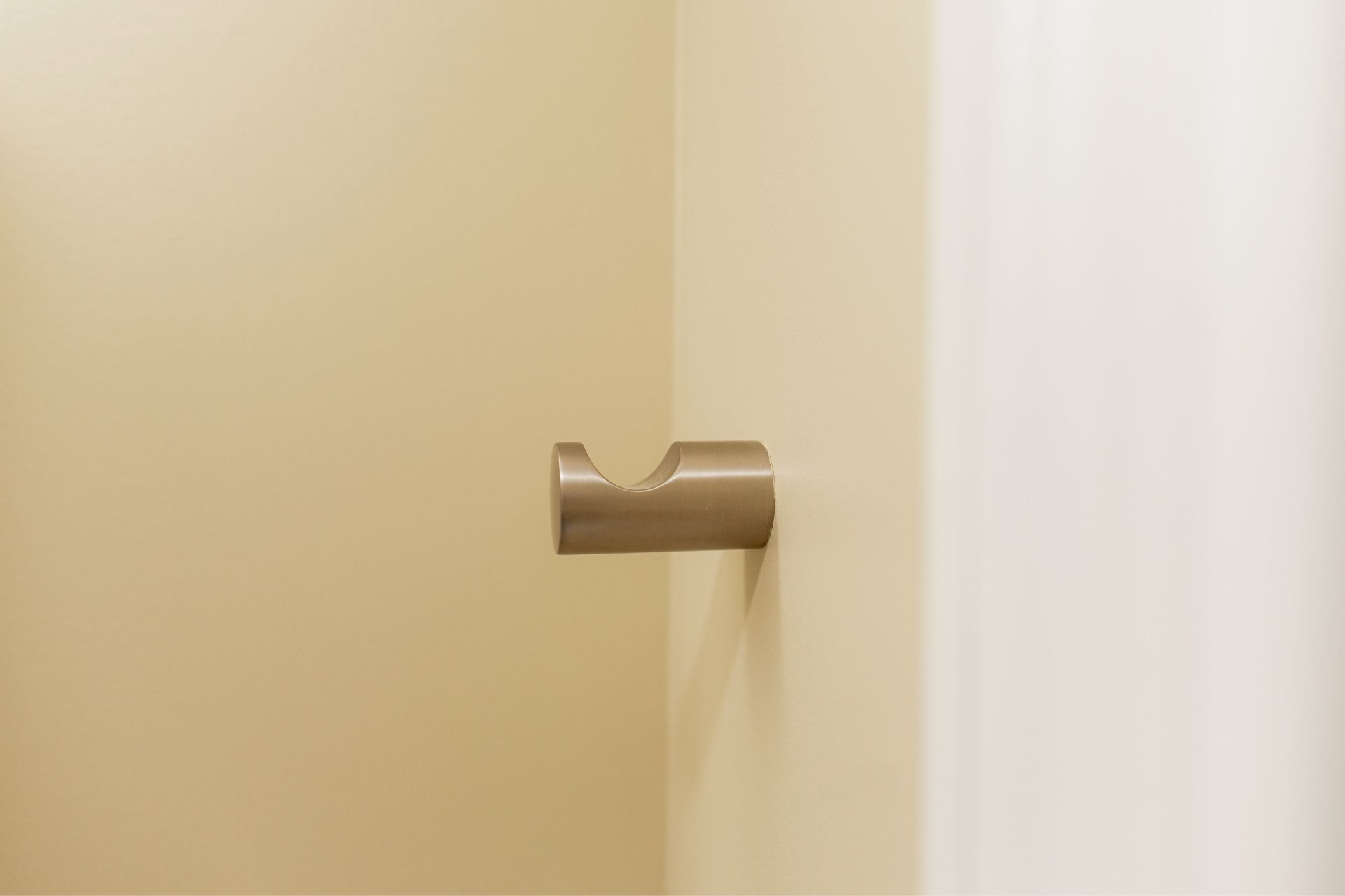 Wall-mounted toilet paper holder on a beige bathroom wall
