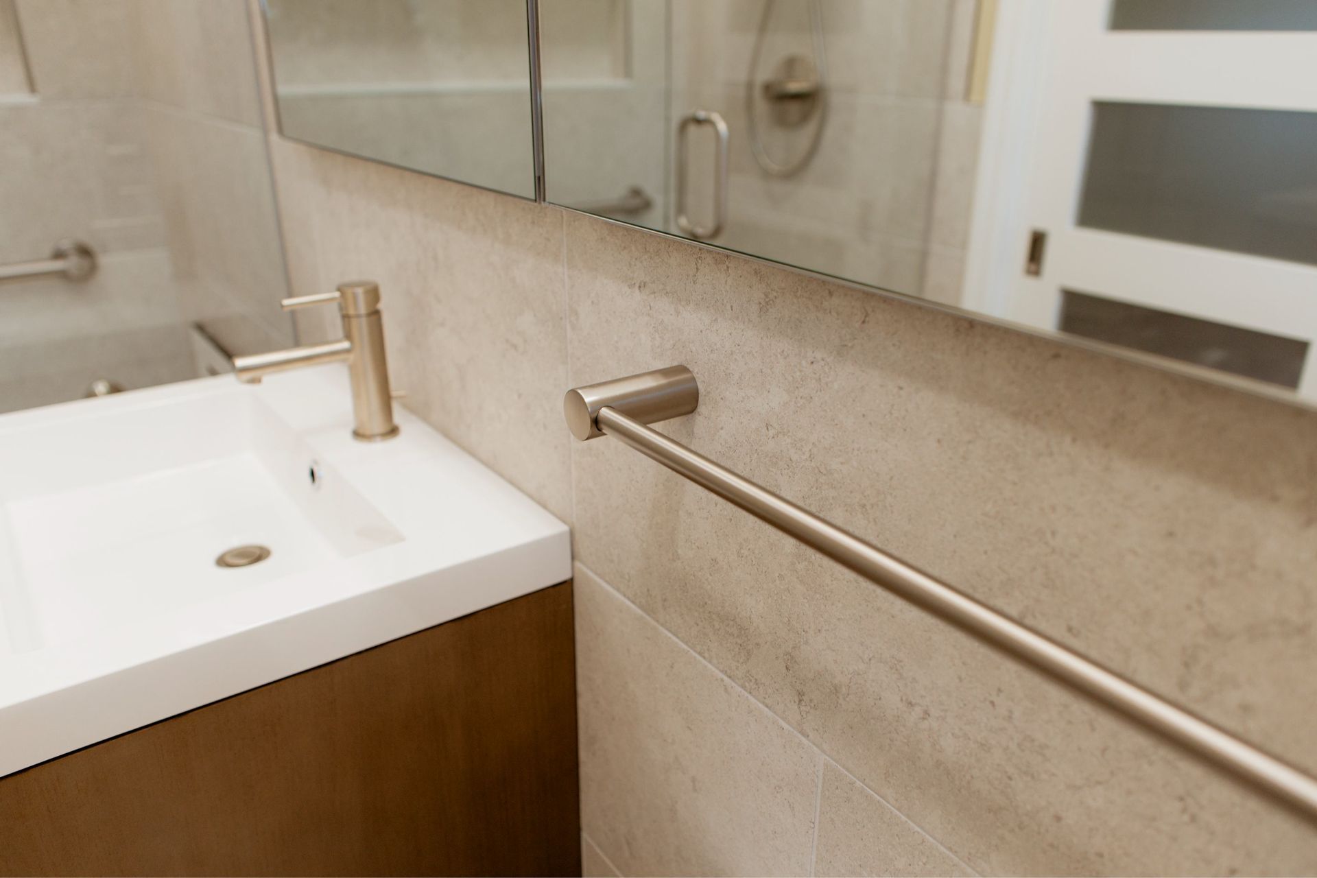 Accessible bathroom sink with wooden vanity, wall mirror, and horizontal grab bar beside the sink