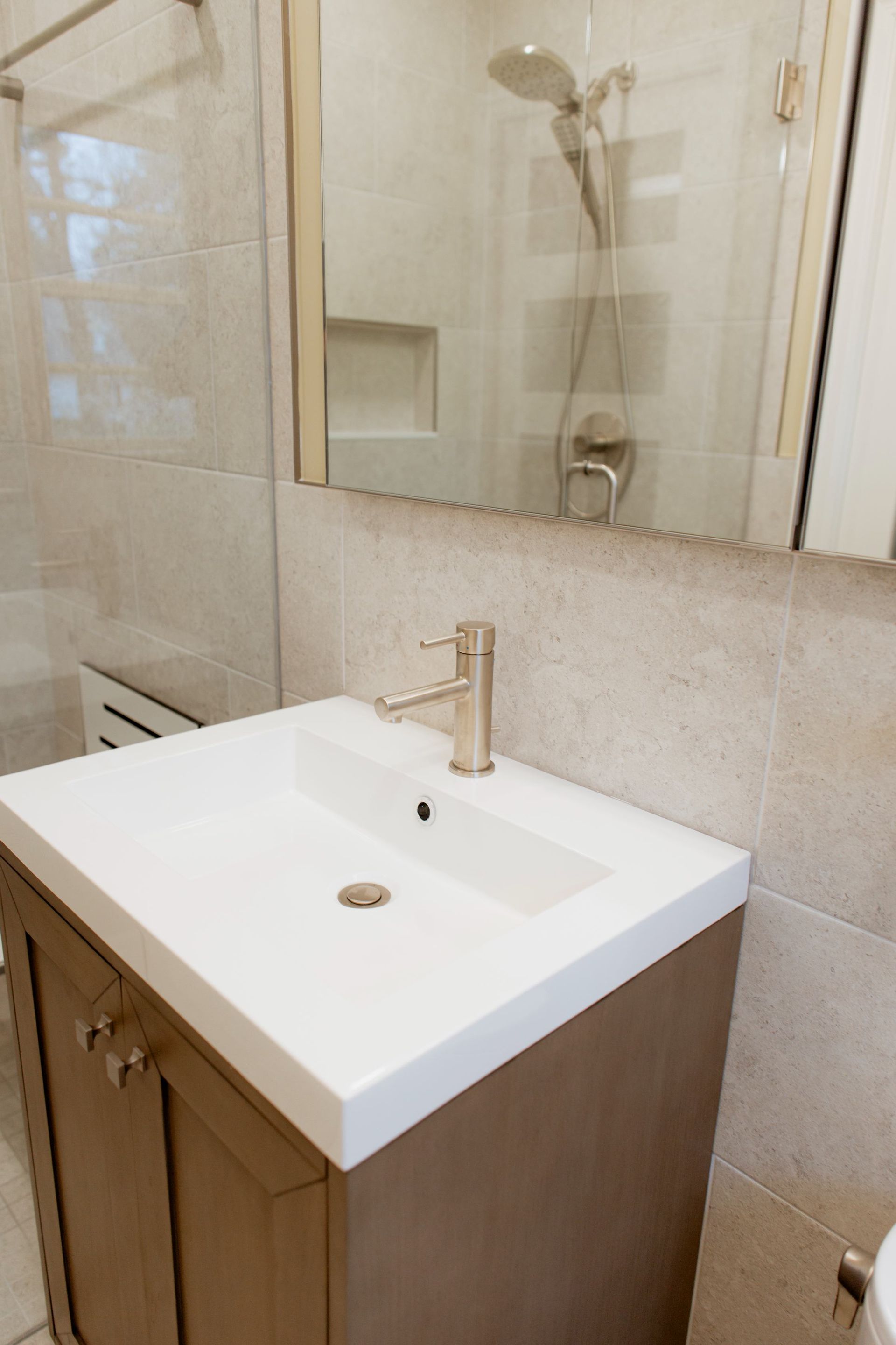 Bathroom vanity with white sink, chrome faucet, and mirror above wood cabinet.
