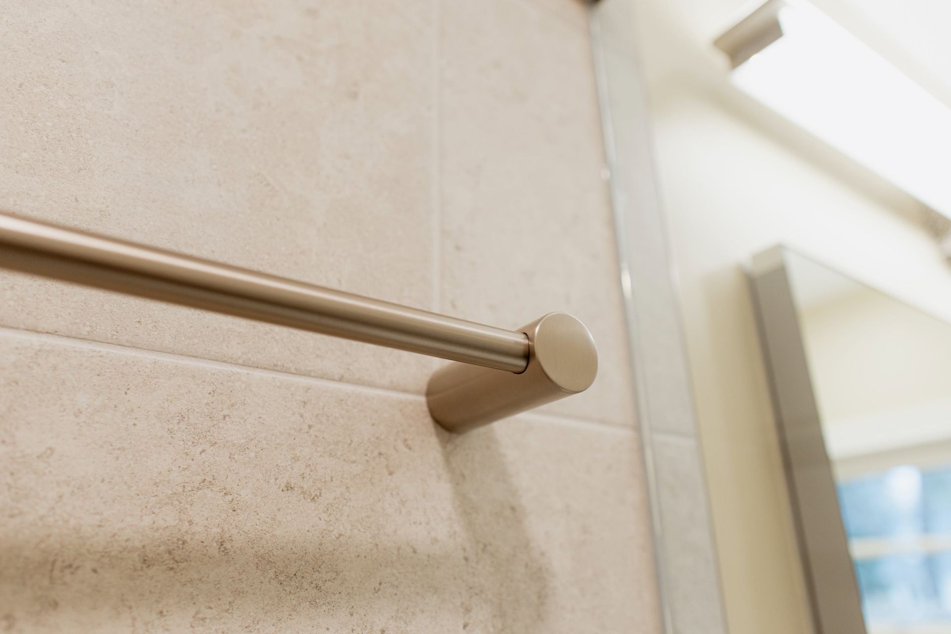 Beige towel bar mounted on a tiled bathroom wall near a shower window