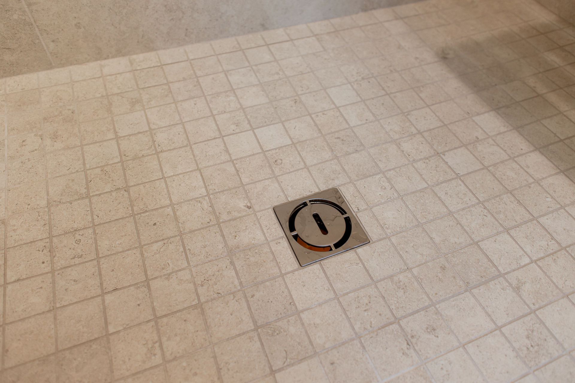 Square tile floor with a centered circular floor drain or access cover.