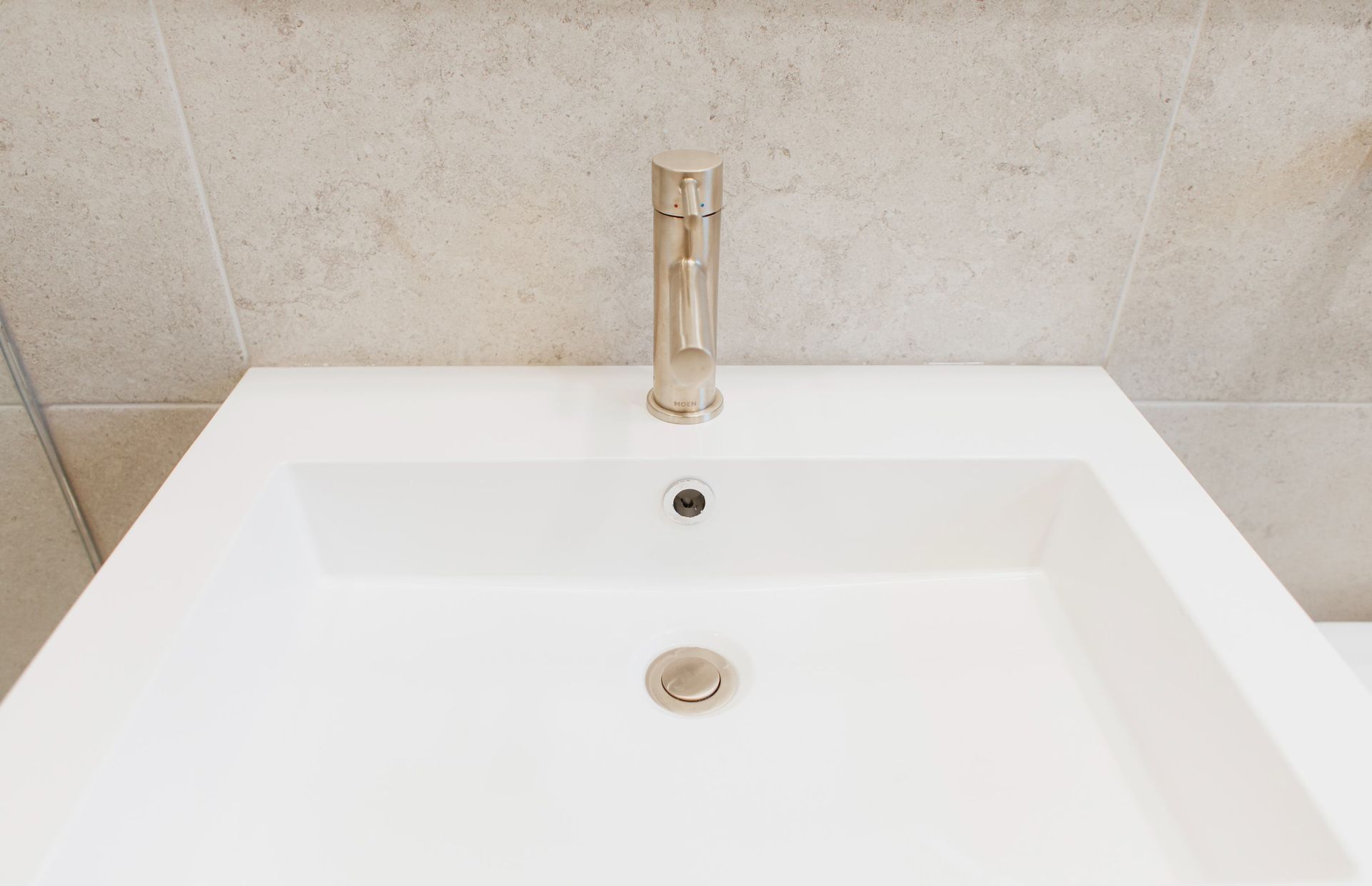 White bathroom sink with chrome faucet and beige tiled backsplash