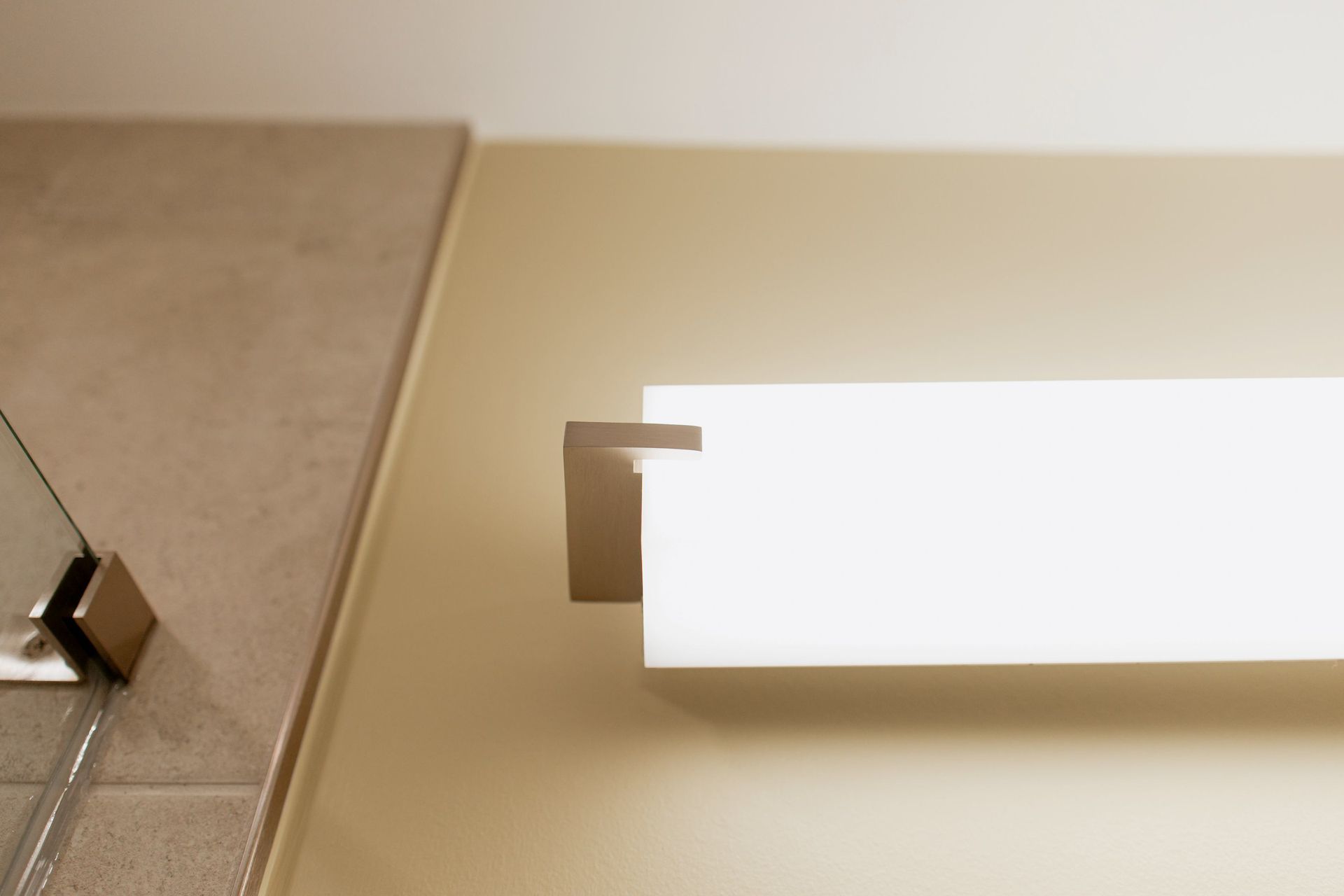 White wall light mounted on a beige wall beside a tiled surface