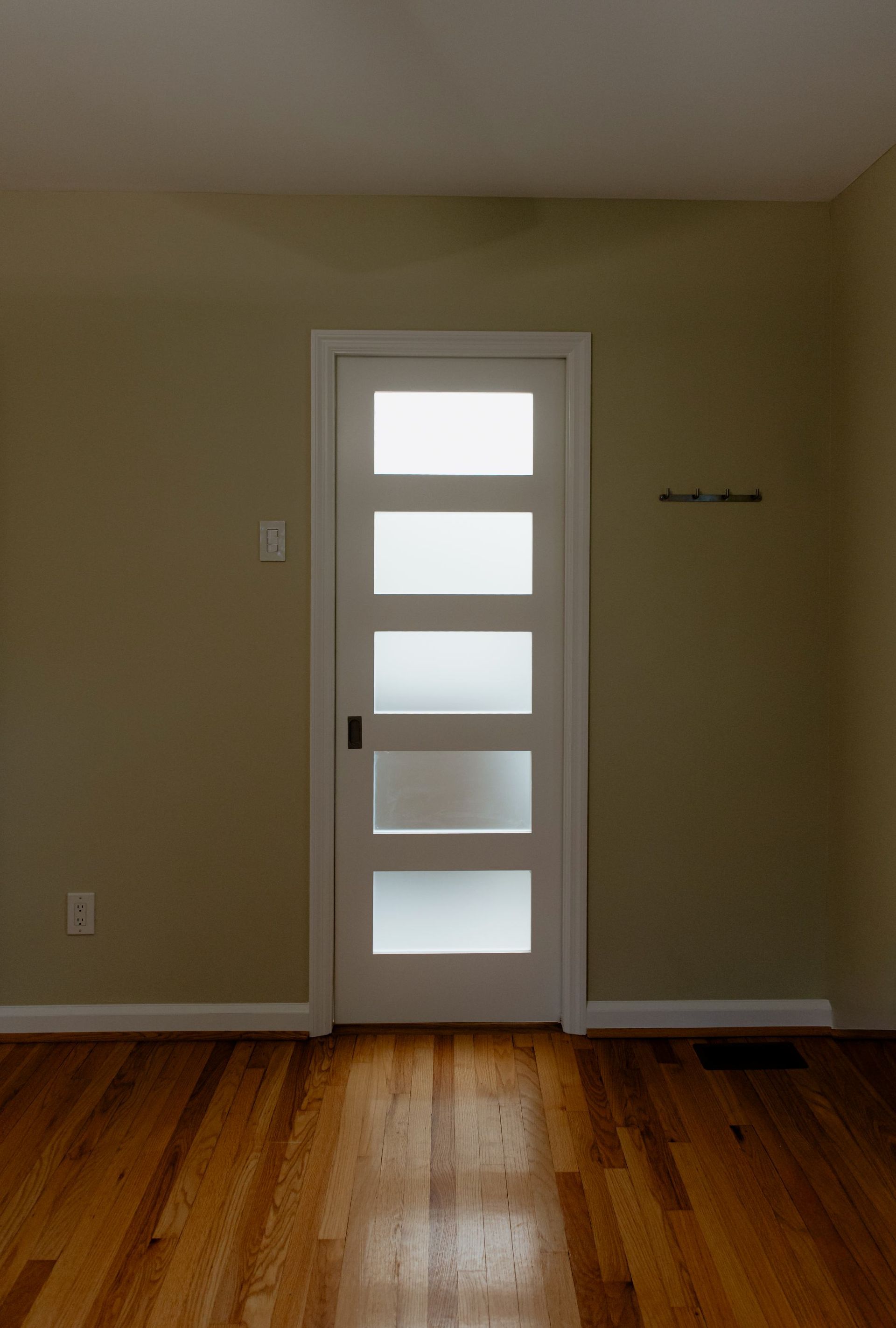 Empty room with hardwood floor and a white door with frosted glass panels.