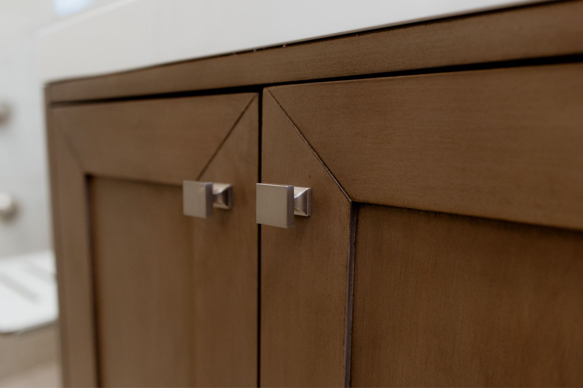 Wooden cabinet with two square metal handles and a visible corner seam