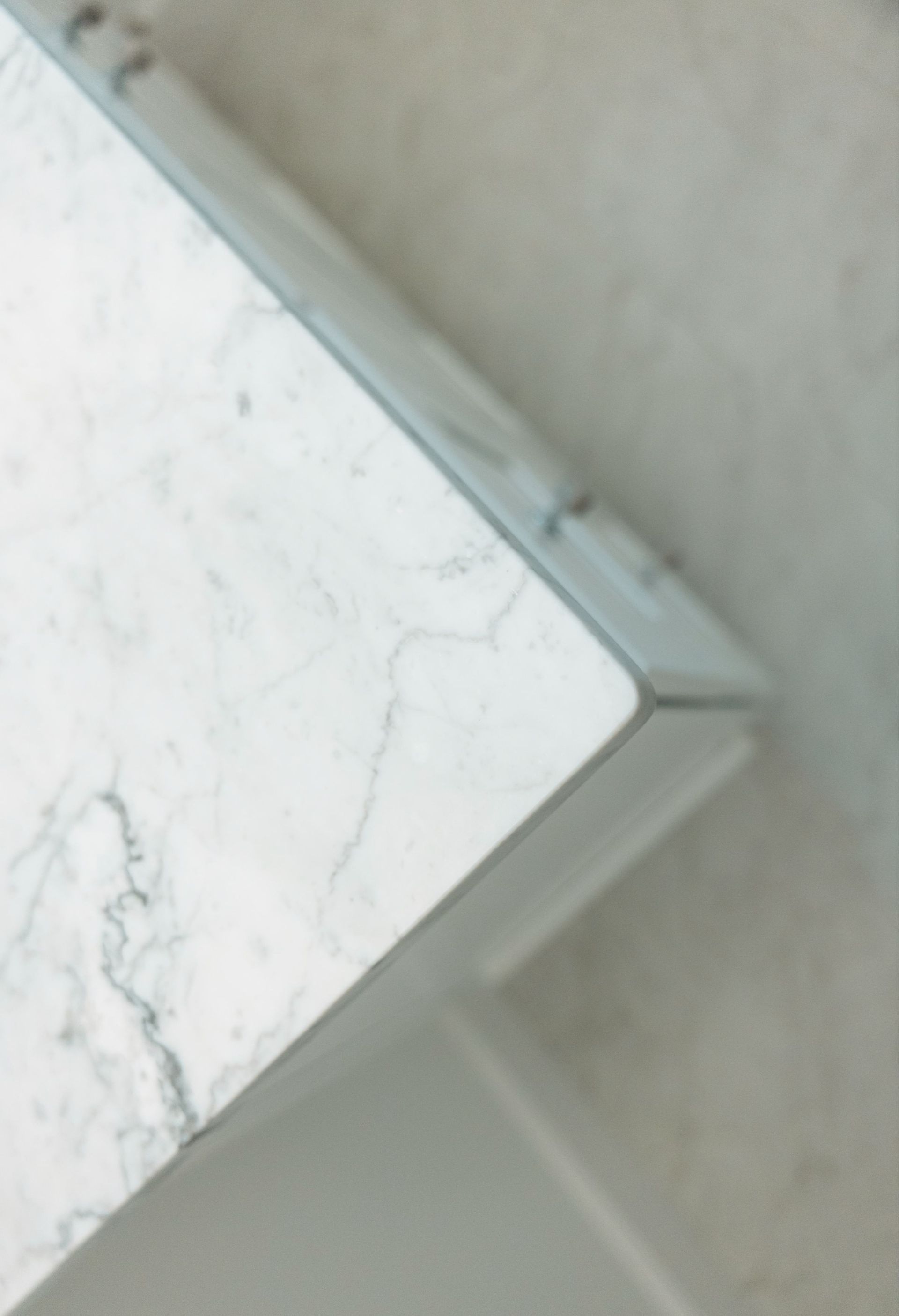White marble tabletop corner against a light gray wall with a small dark mark on the edge