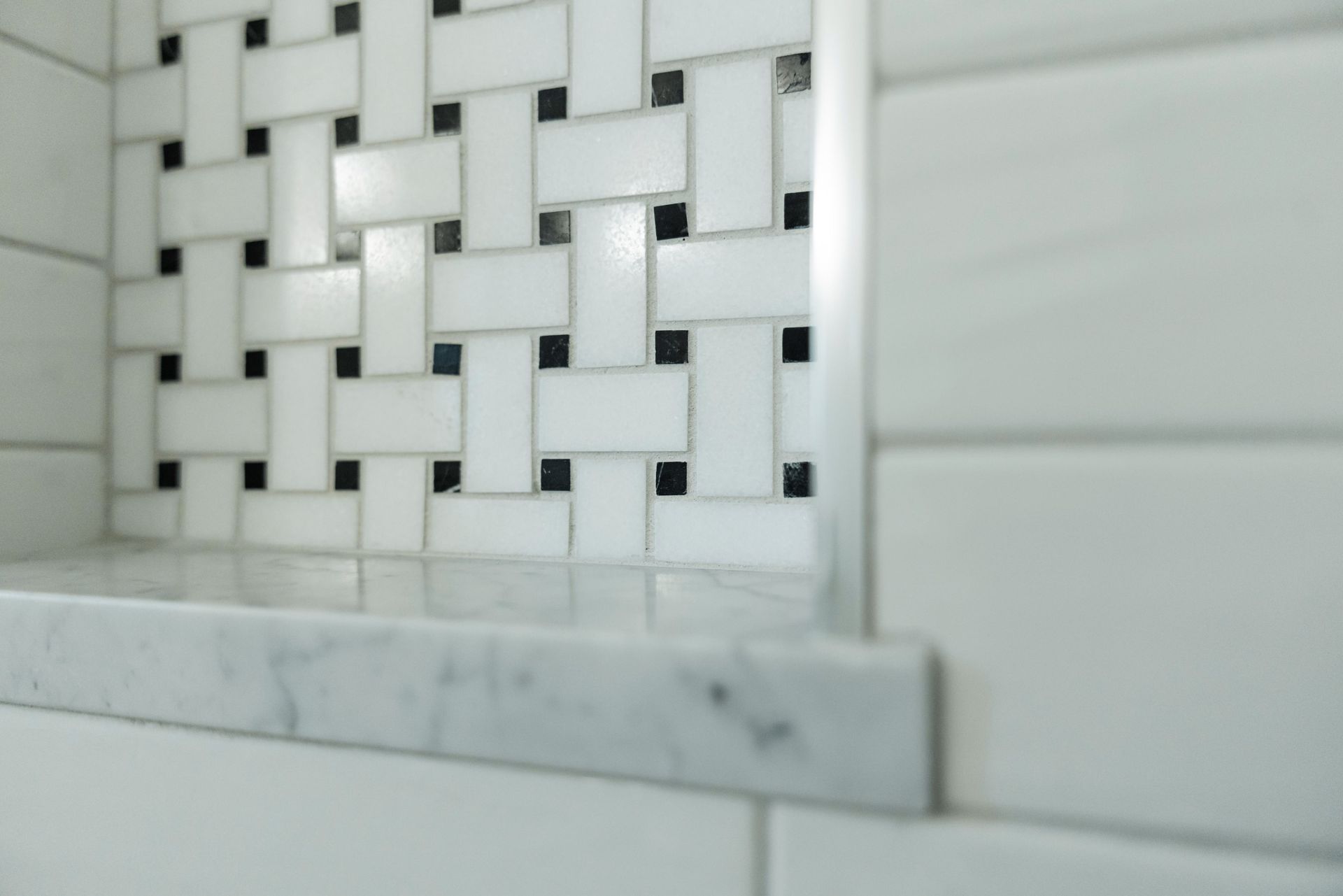 White and gray tiled wall with a small marble ledge in a bathroom or kitchen corner
