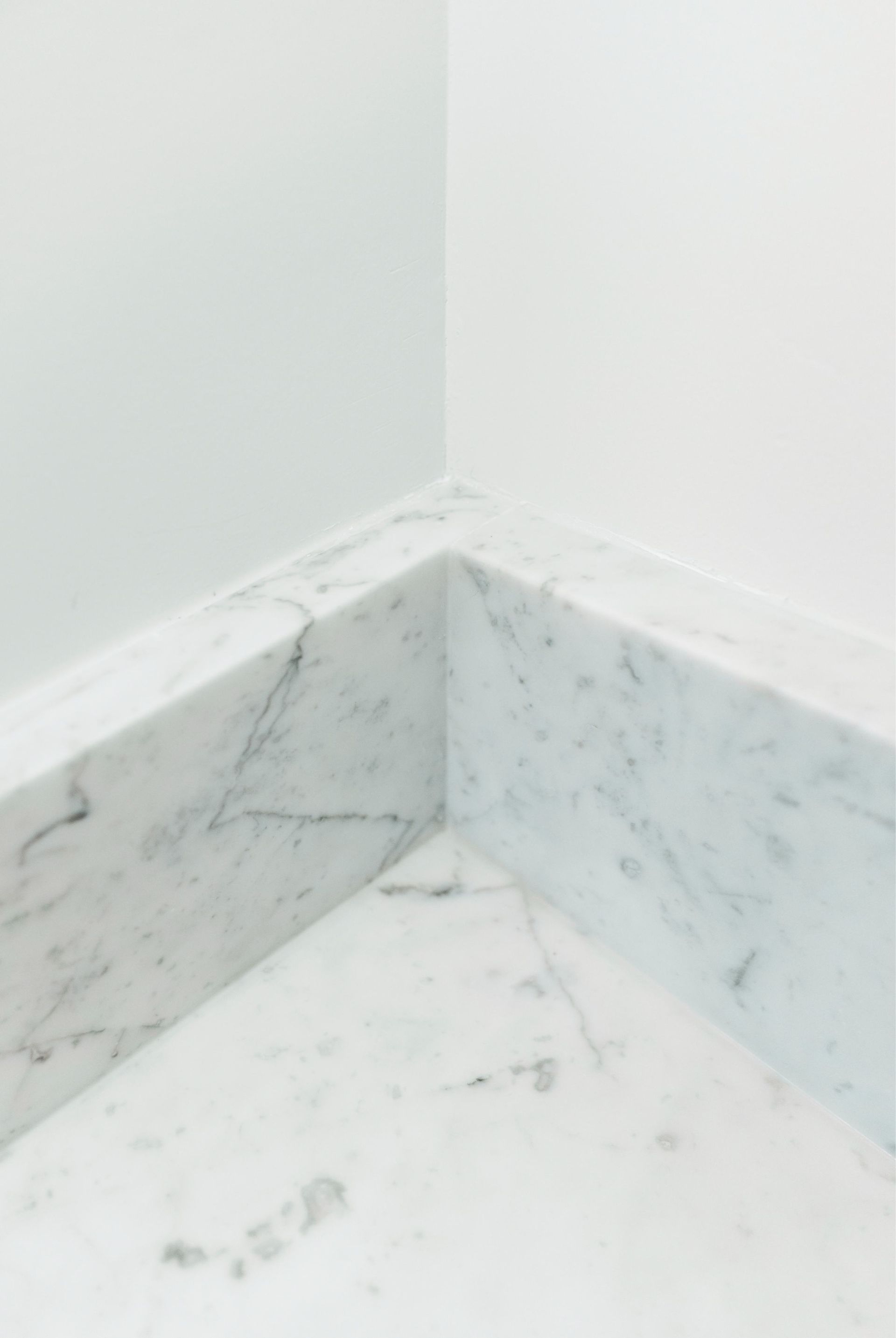 Corner of a room with white walls and marble-patterned tile trim and floor.