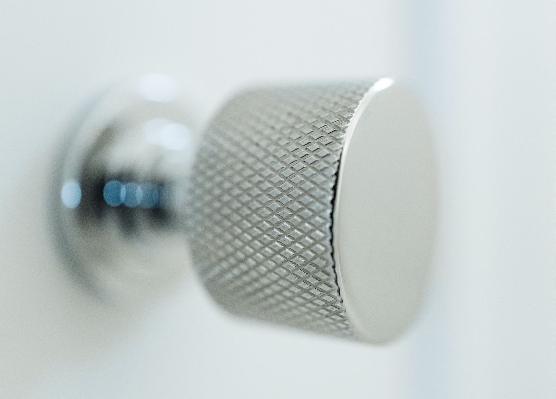 Close-up of a silver textured knob on a white surface