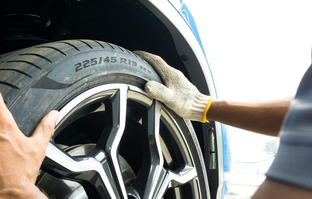 Hands cleaning a car wheel with a tire marked 225/45 R15.