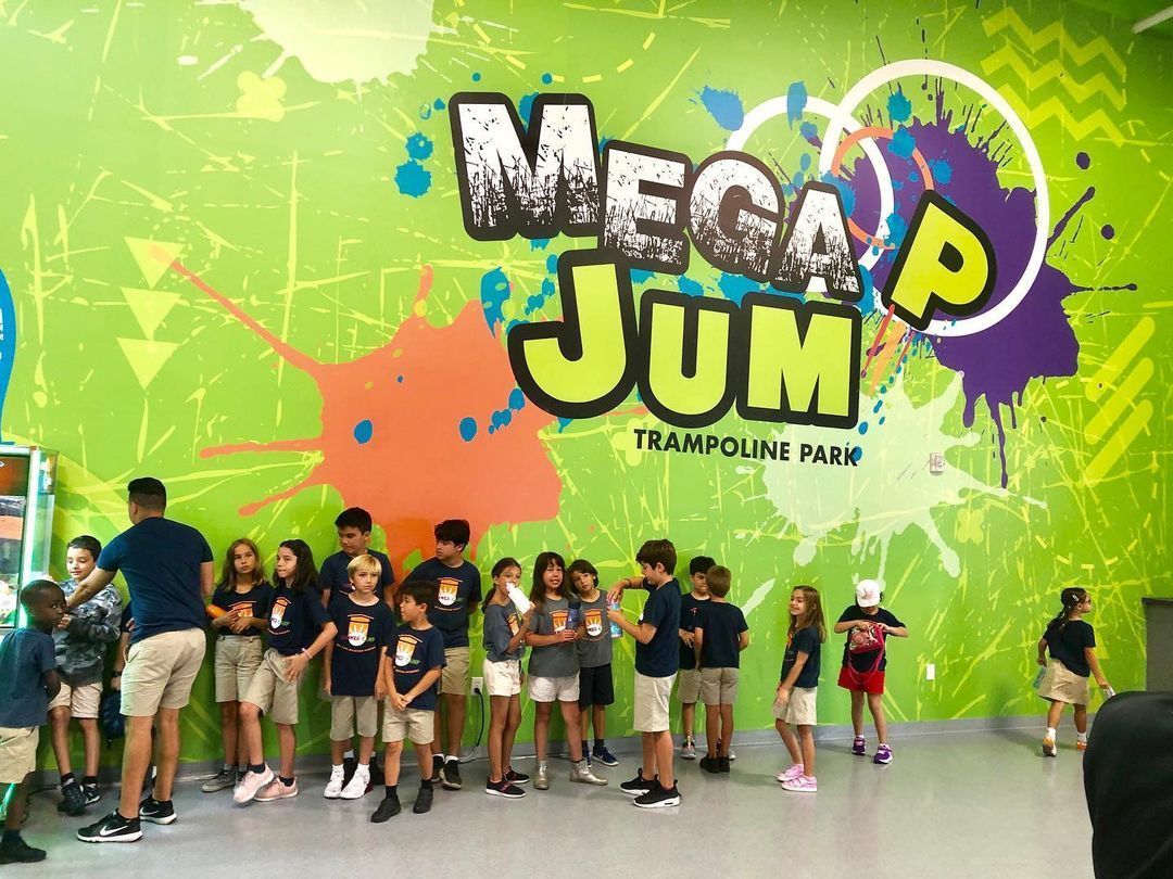 Group of children at Mega Jump Trampoline Park, standing in front of a splash-painted wall.