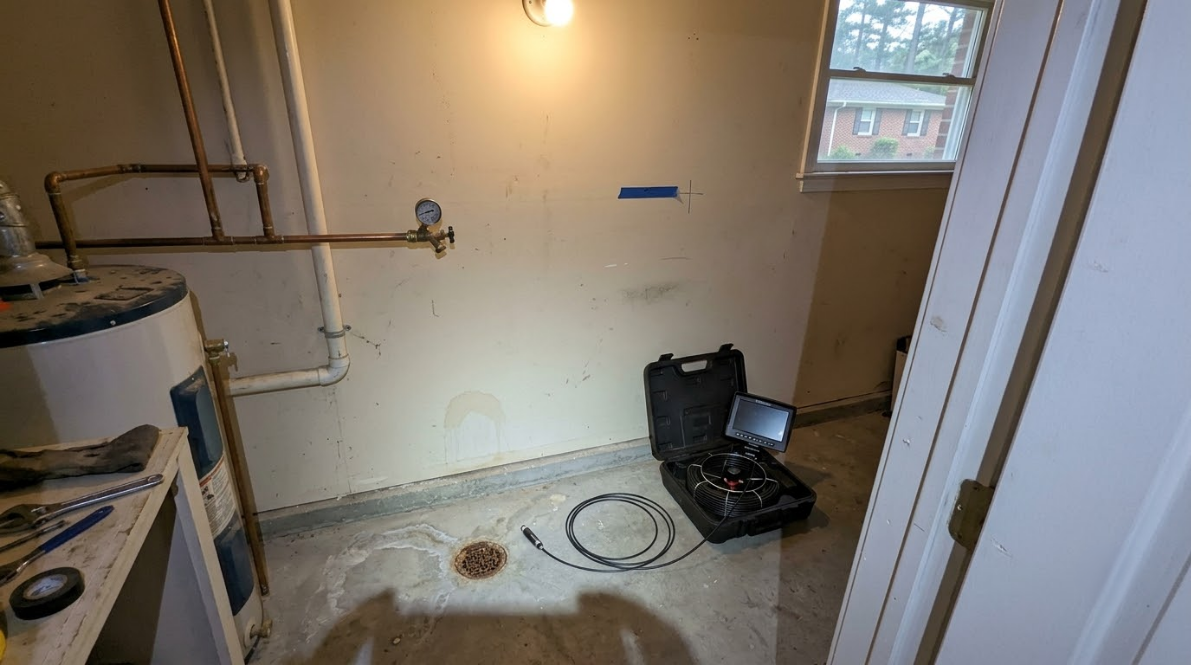 Partially finished laundry/utility room with exposed pipes, a washer, and tools on the floor